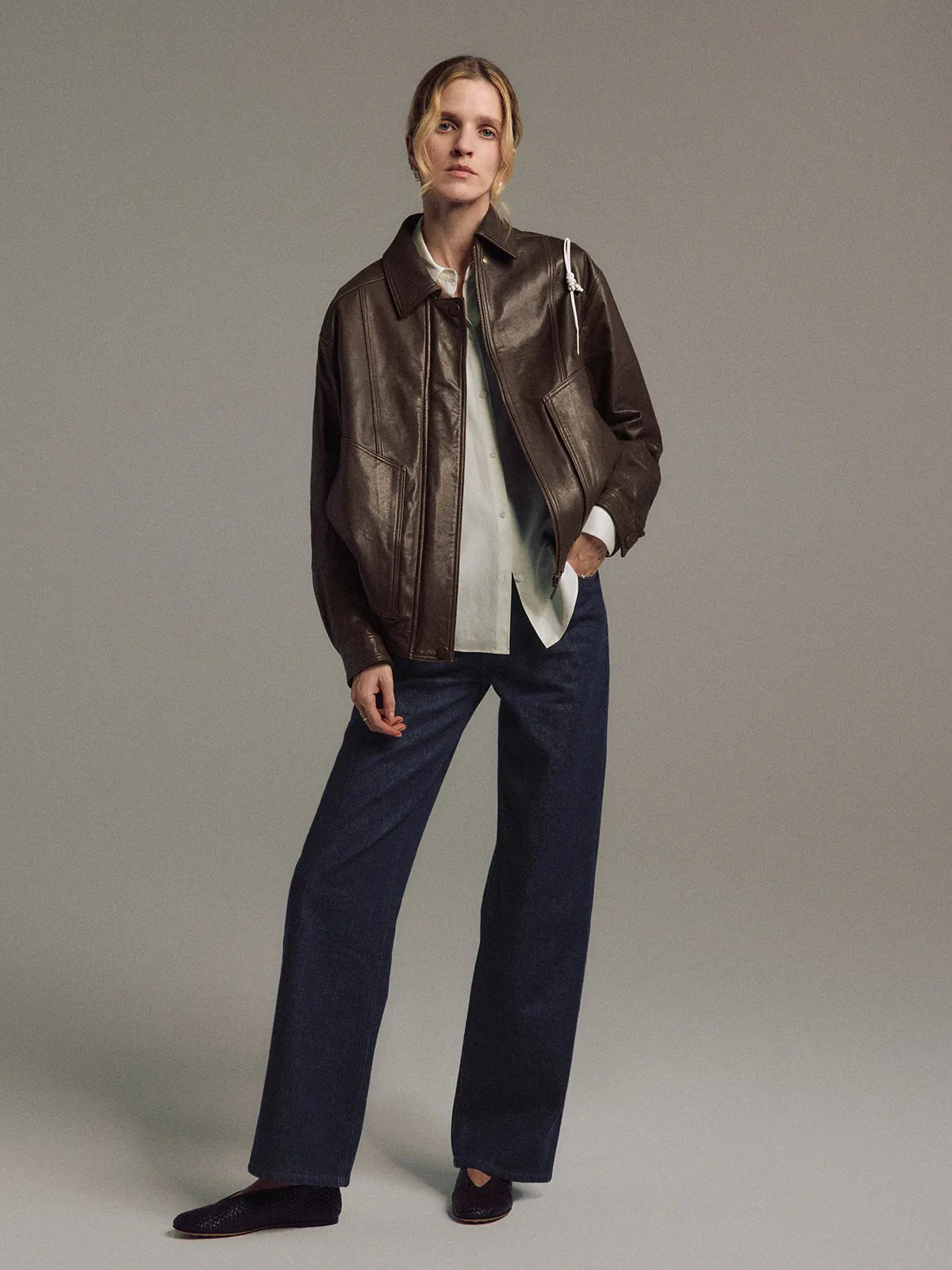 Front view of model wearing Blue raw denim straight-leg jeans, blouse, and dark loafers.
