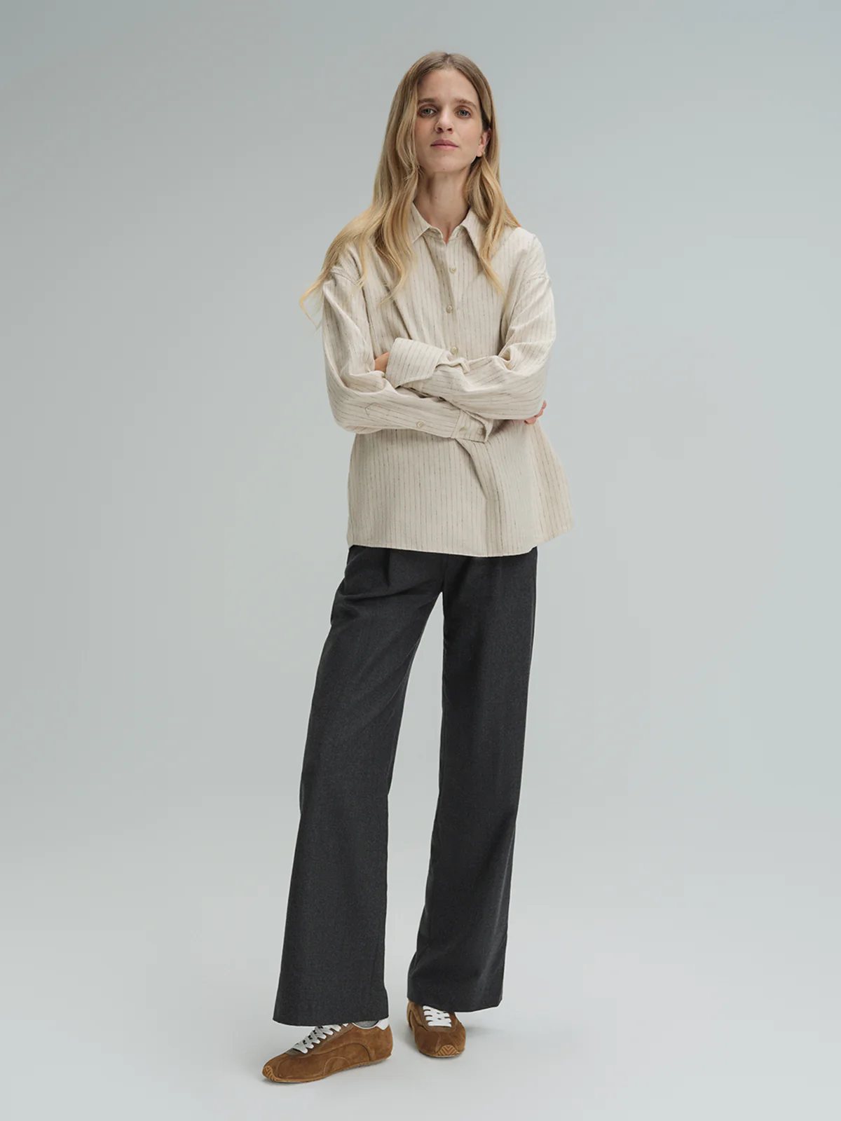 Model in andreatang dark grey wool straight-leg trousers with beige striped shirt