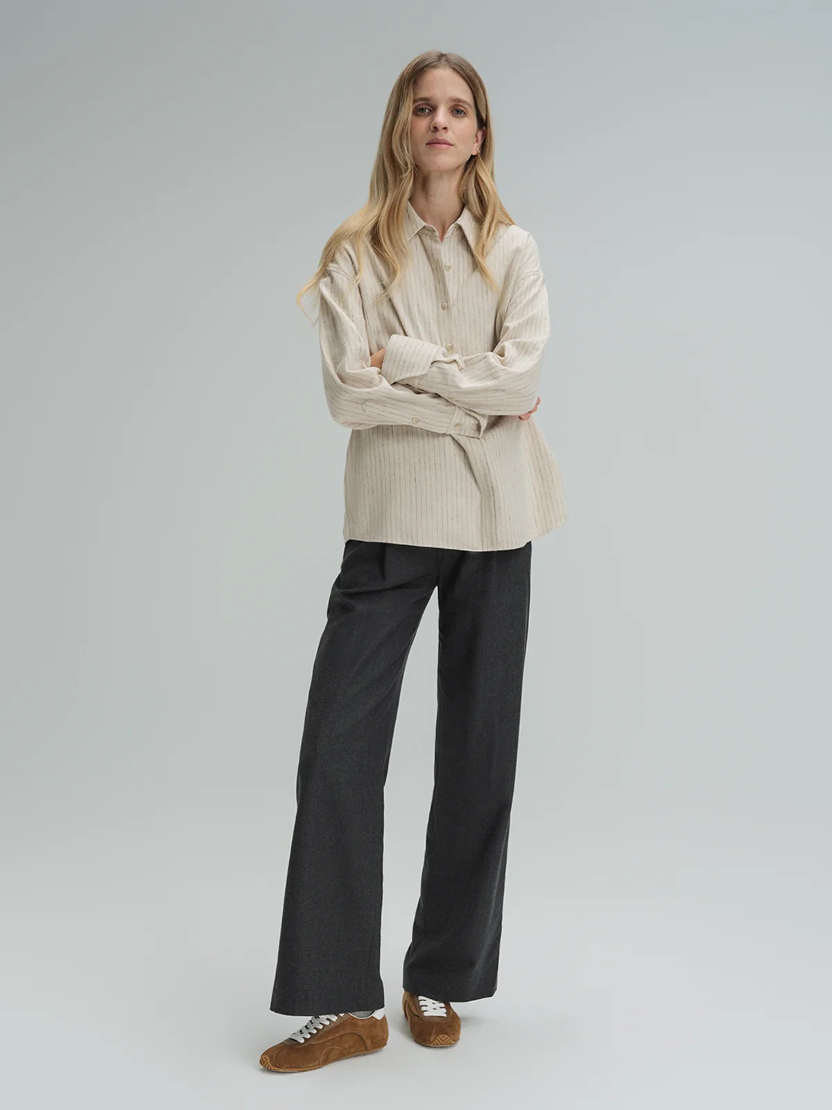 Model in andreatang dark grey wool straight-leg trousers with beige striped shirt