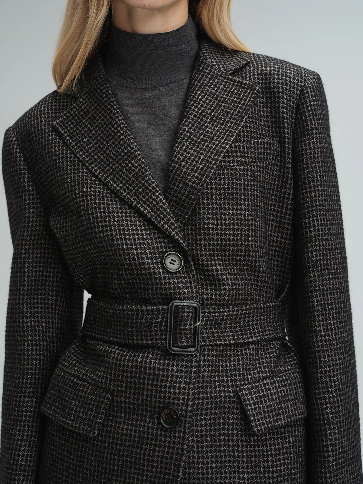 Close-up of andreatang black and grey houndstooth wool-blend blazer with belt and button details