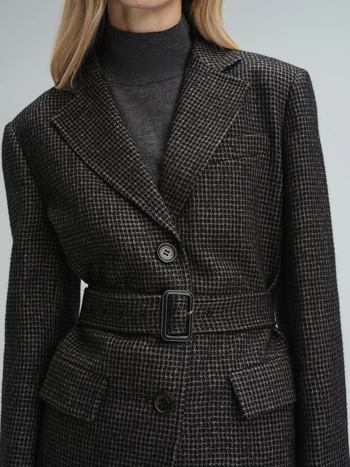 Close-up of andreatang black and grey houndstooth wool-blend blazer with belt and button details