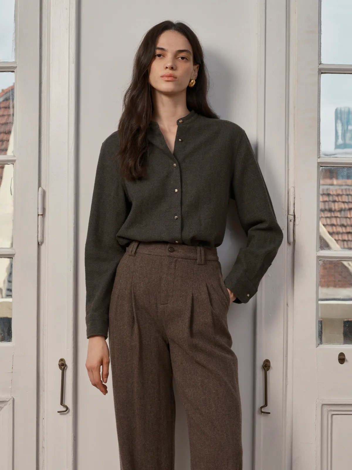 Model wearing WINSLOW shirt with brown wool trousers, standing by French doors