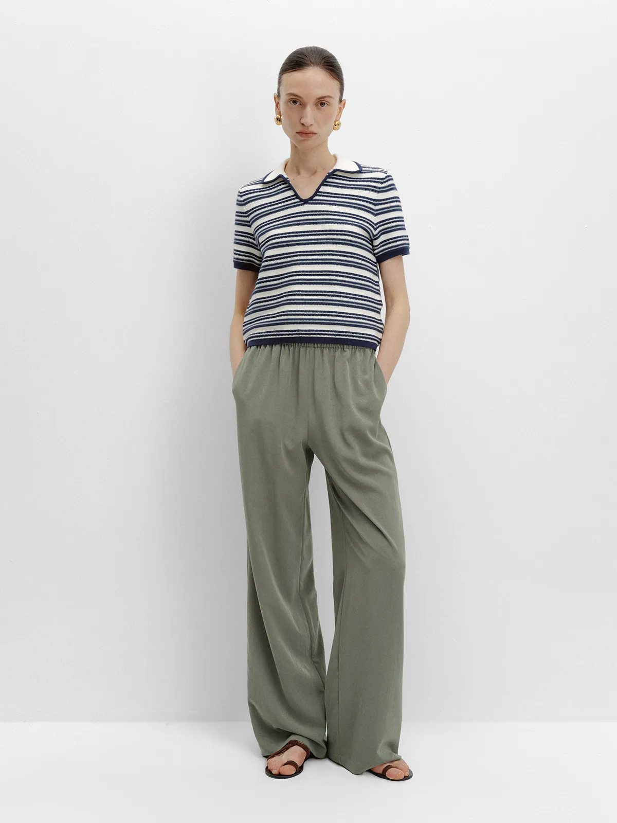 andreatang ANGELINA striped knit polo t-shirt in navy and ivory worn with olive green wide-leg trousers and leather sandals, full-body front view