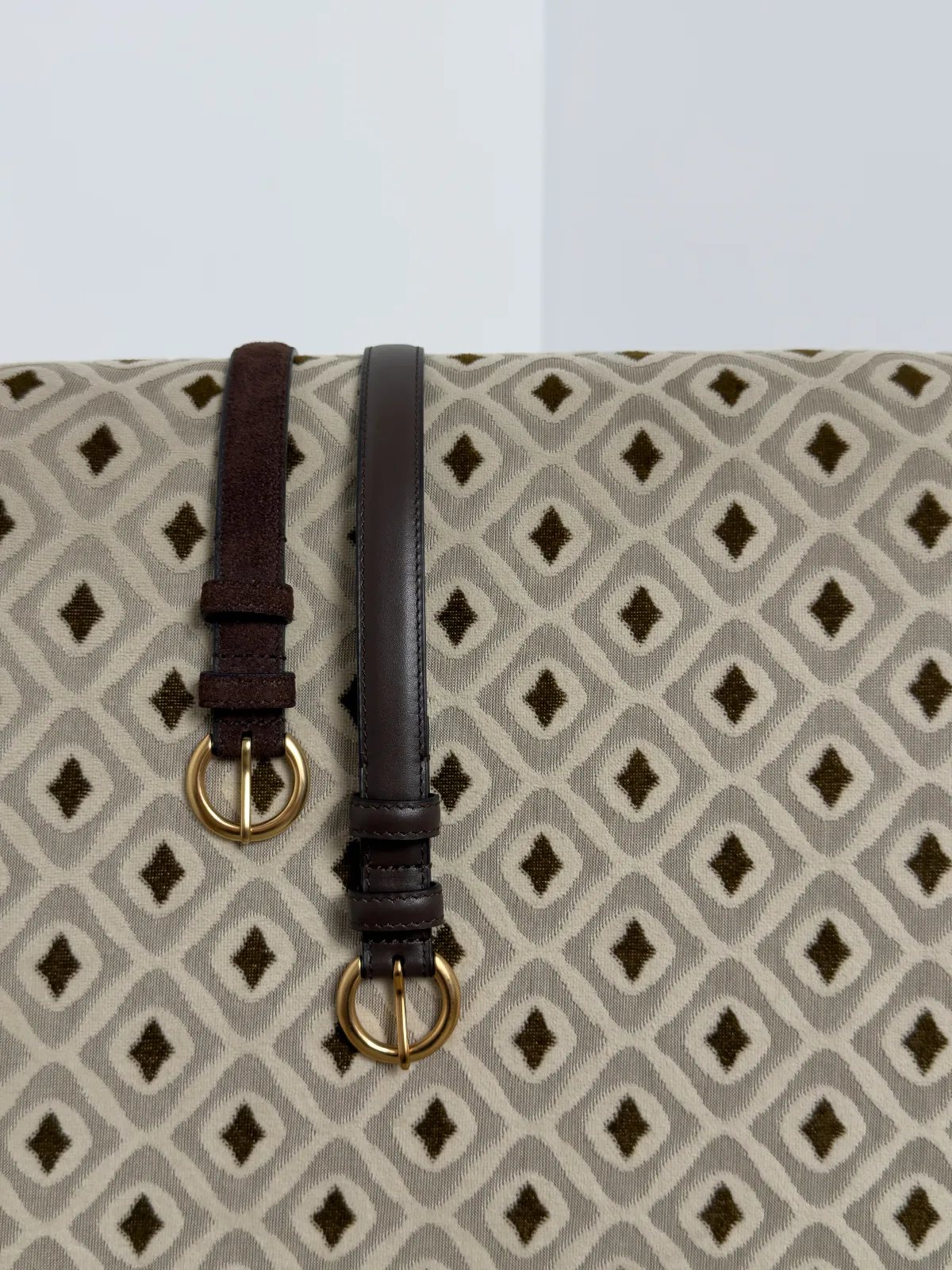 RANGER suede belt and matching smooth leather belt displayed on geometric textile background