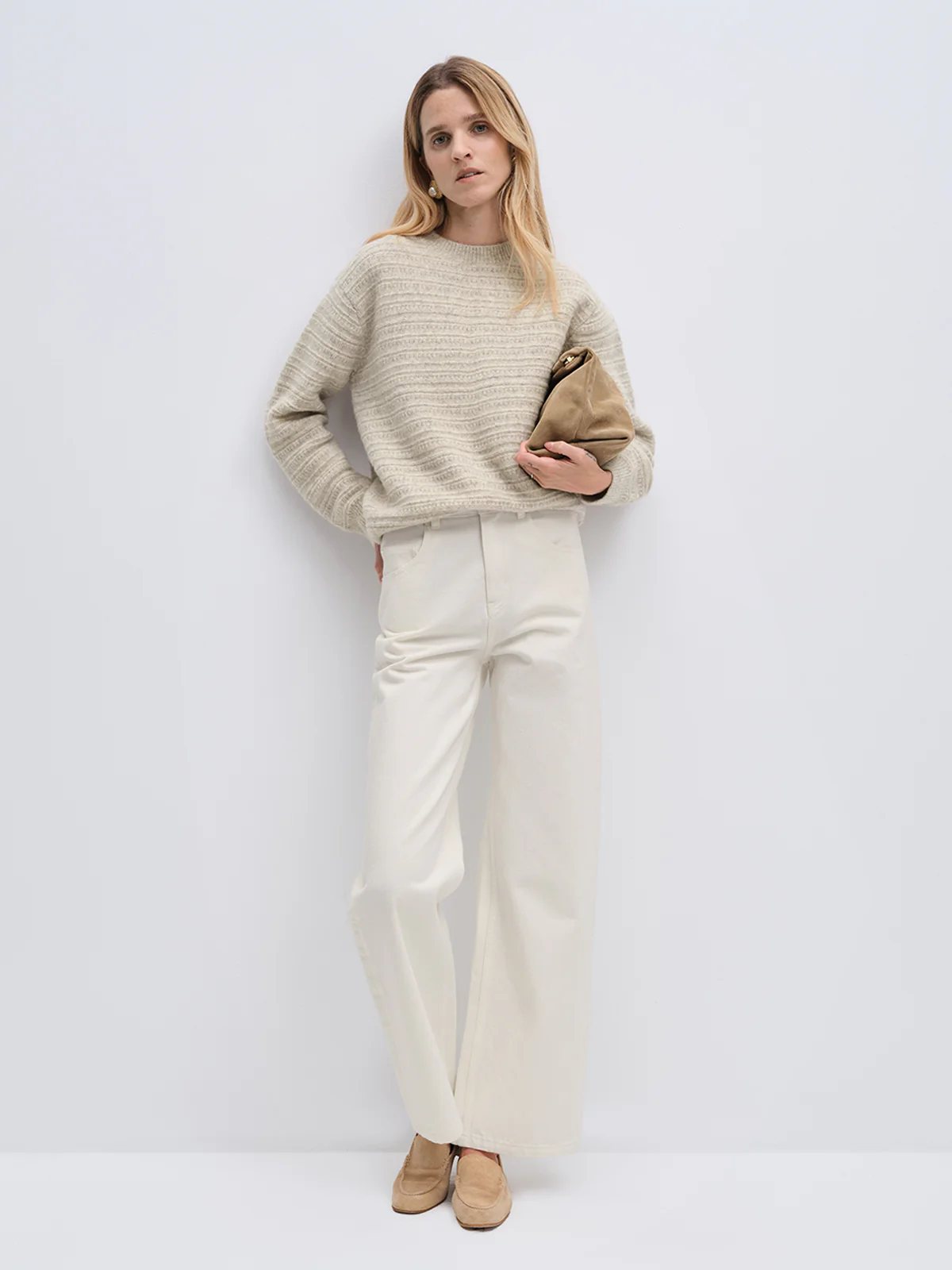 Model wearing andreatang wool-cotton jacquard sweater in oatmeal and blue-grey painterly stripe with ivory wide-leg jeans