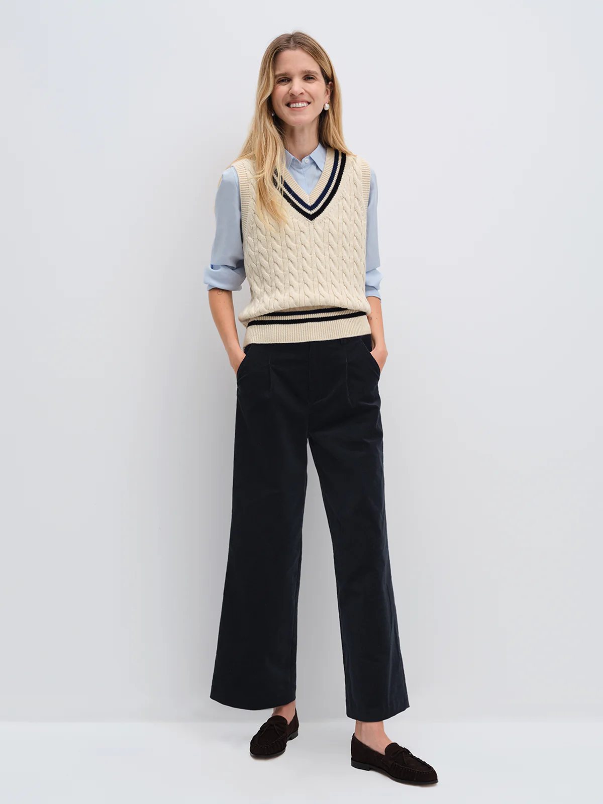 Model wearing andreatang cream cricket vest with blue shirt and navy wide-leg pants, tassel loafers