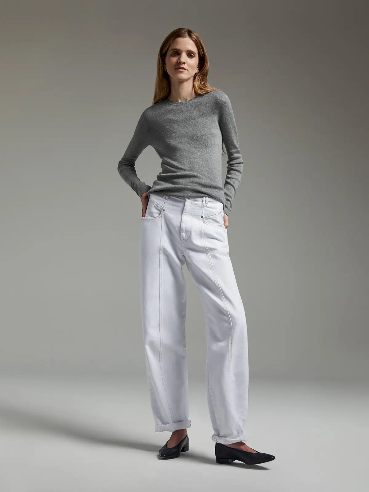 Model wearing a grey slim fit long-sleeve knit top with crew neck and wide-leg jeans.