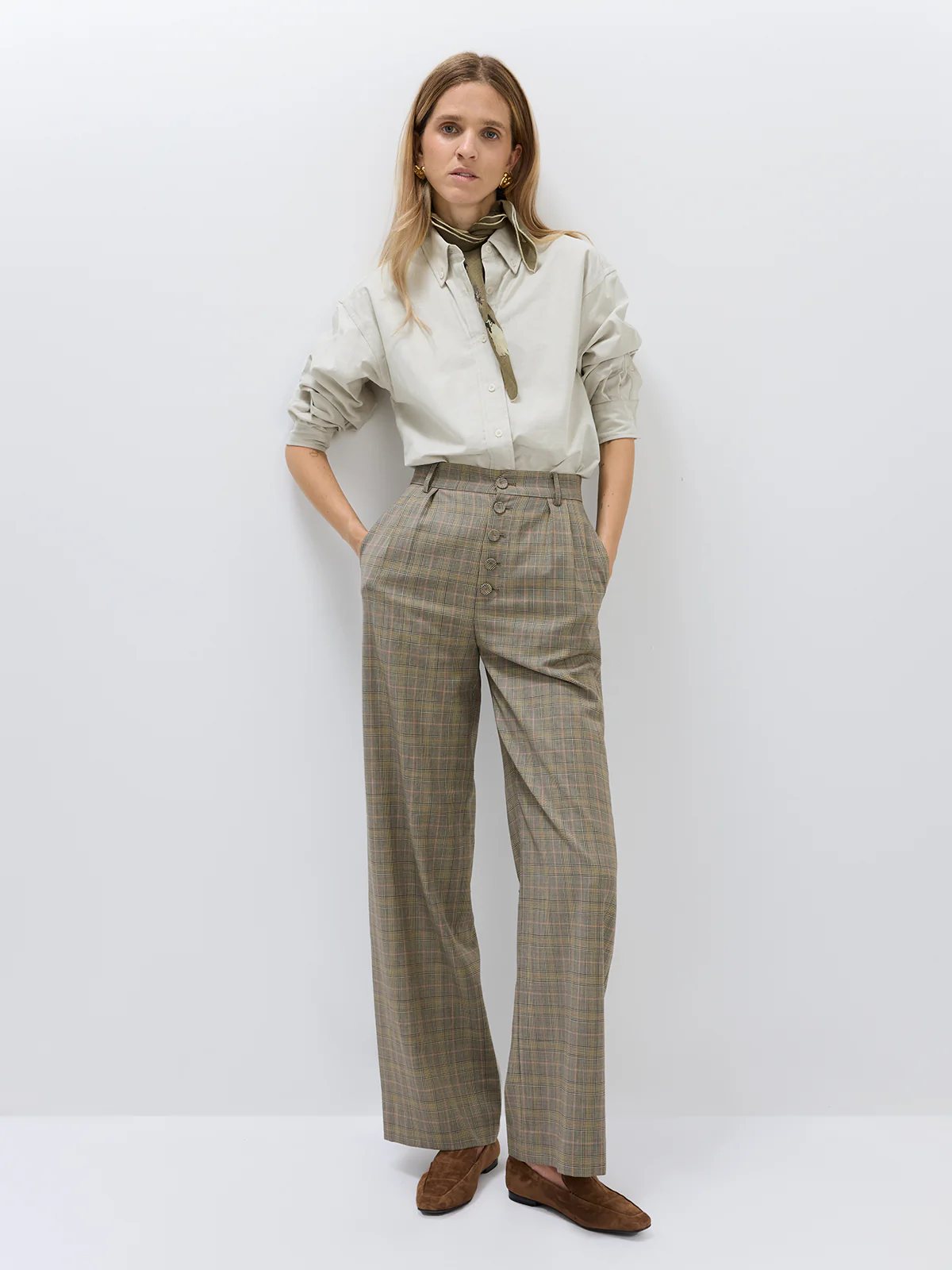 Front view of model in wide-leg Prince of Wales check trousers with high waist, button closure, and relaxed fit.