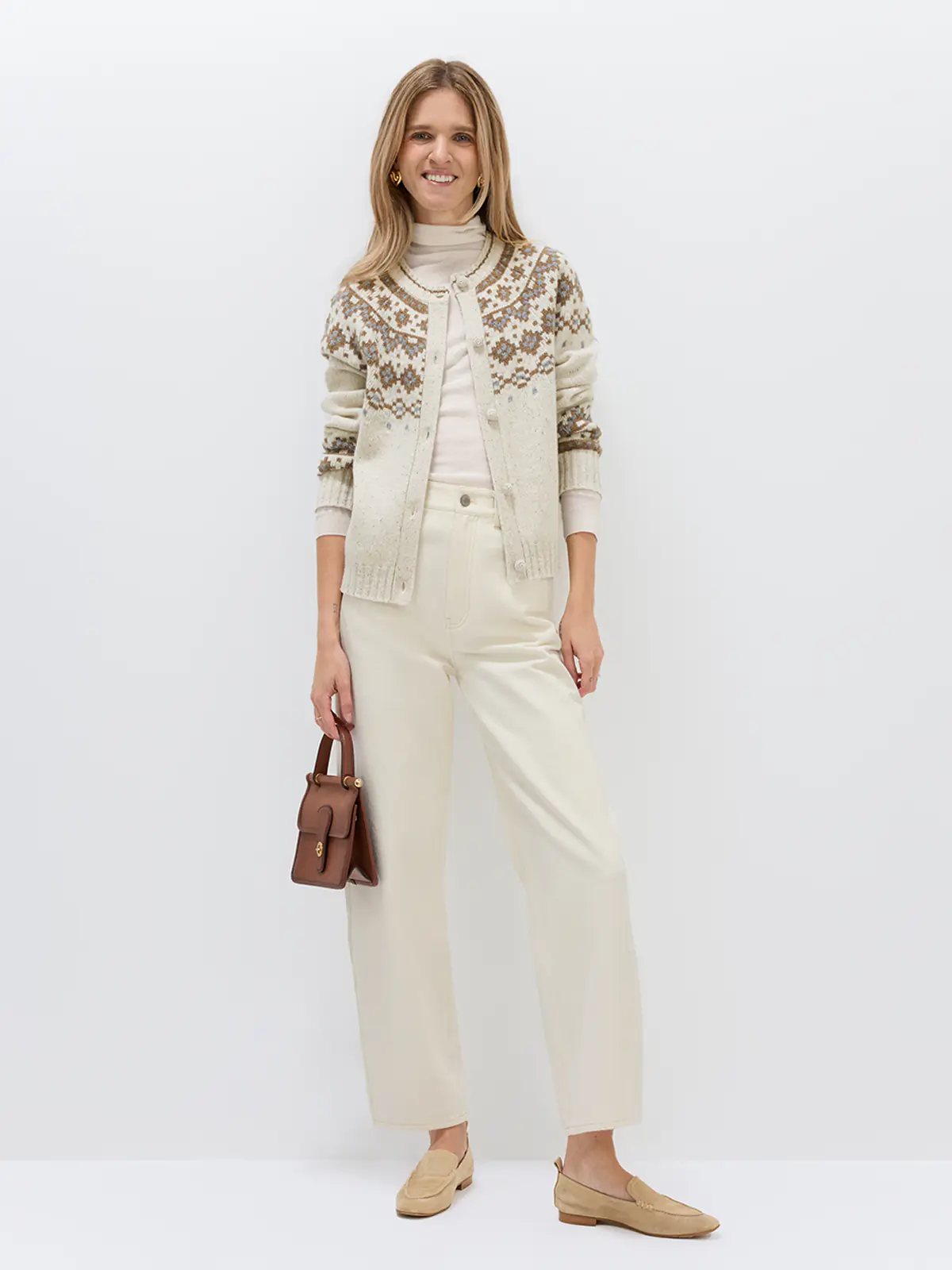 Front view of model in an Oatmeal Fair Isle cardigan with geometric motifs, hands on hips, paired with a mini skirt and boots.