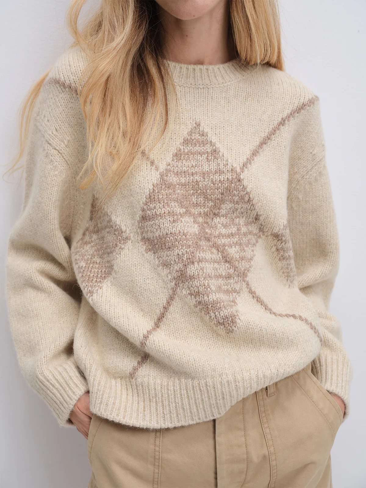 Model wearing the Oatmeal PHOEBE jacquard jumper over a turtleneck, paired with a suede mini skirt and hands on hips.