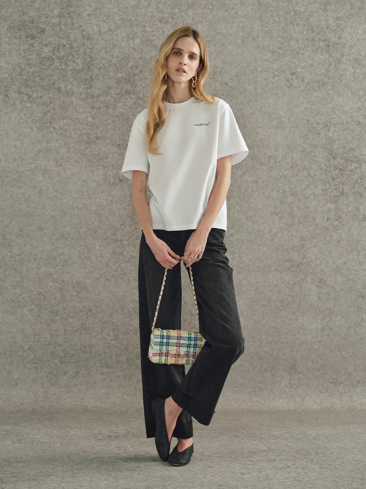 Andreatang white relaxed-fit t-shirt with 'excuse me?' embroidery styled with black wide-leg jeans and plaid tweed bag