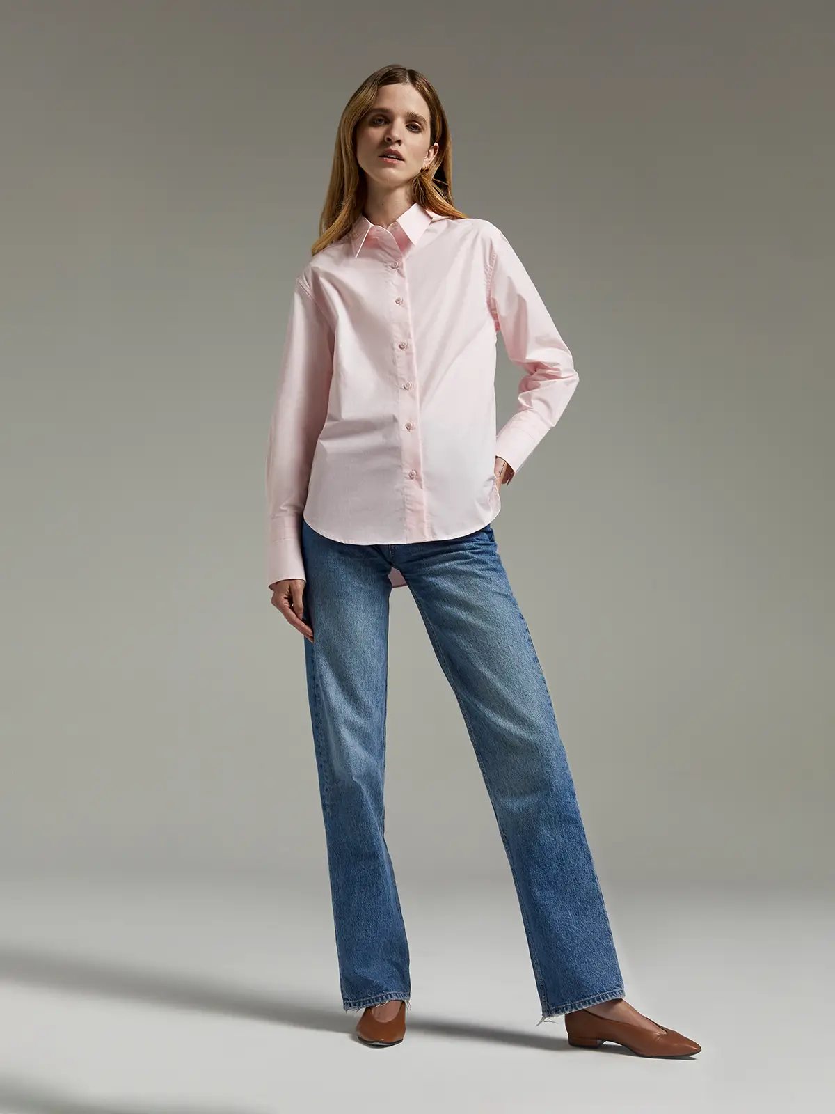 Pink paper-texture cotton shirt worn untucked with jeans and loafers, model standing front-facing.