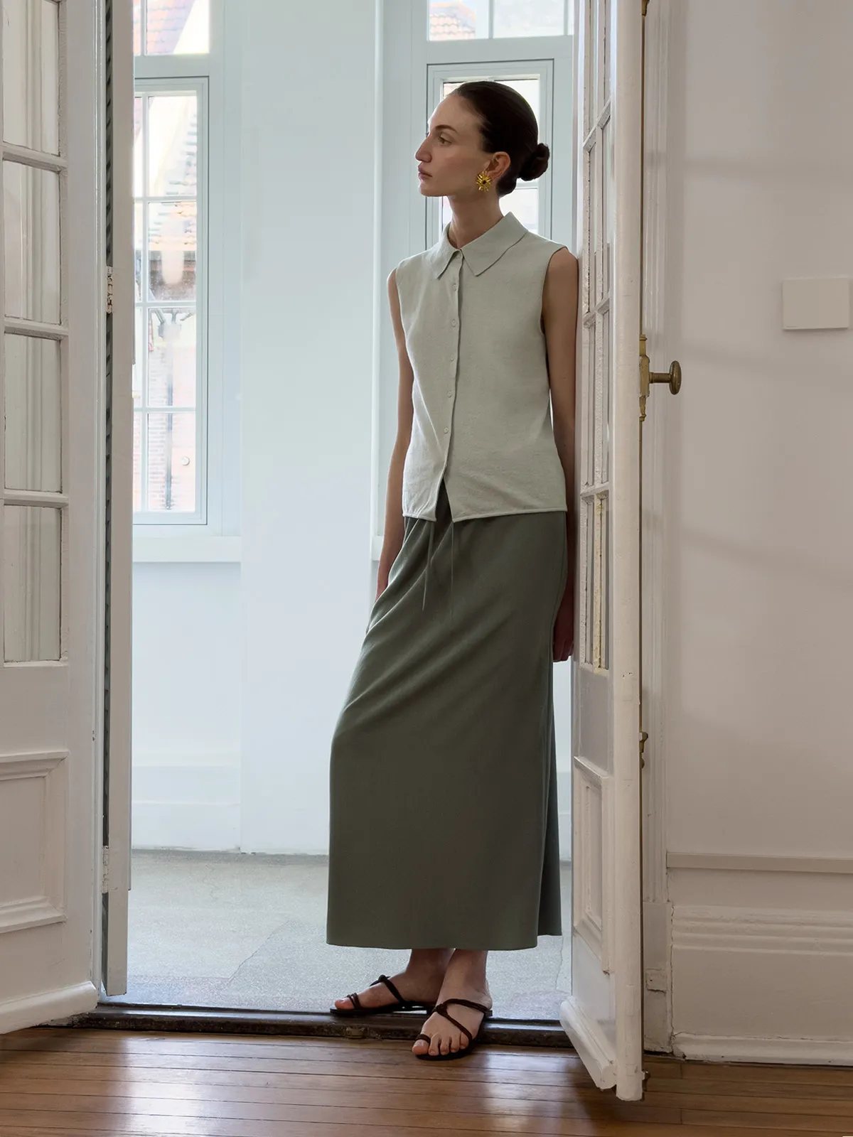 Model in doorway wearing KATRINA midi skirt with sleeveless collar shirt and brown sandals