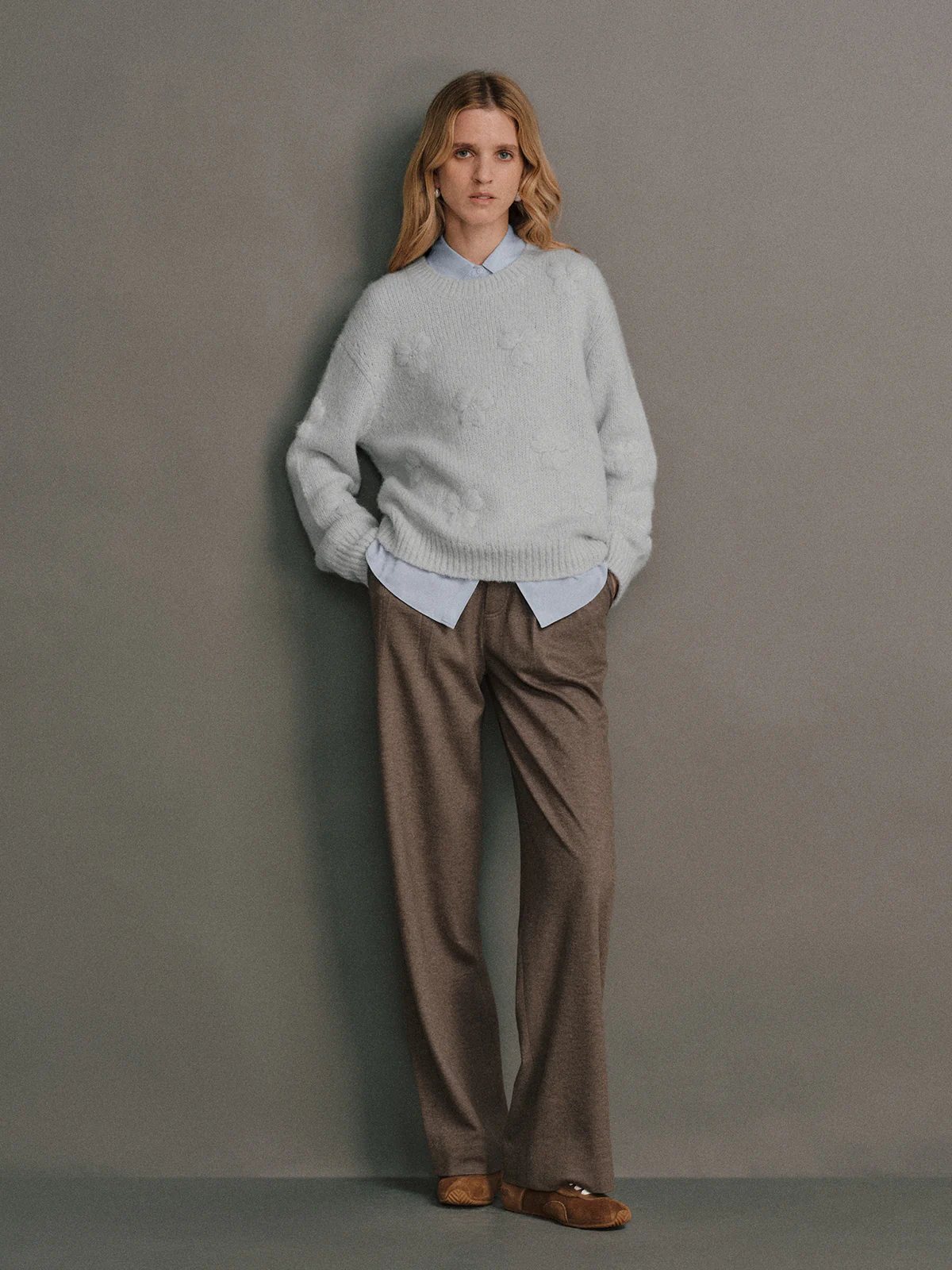 Front view of a model wearing a Light blue alpaca wool embroidered jumper layered over a collared shirt with trousers.