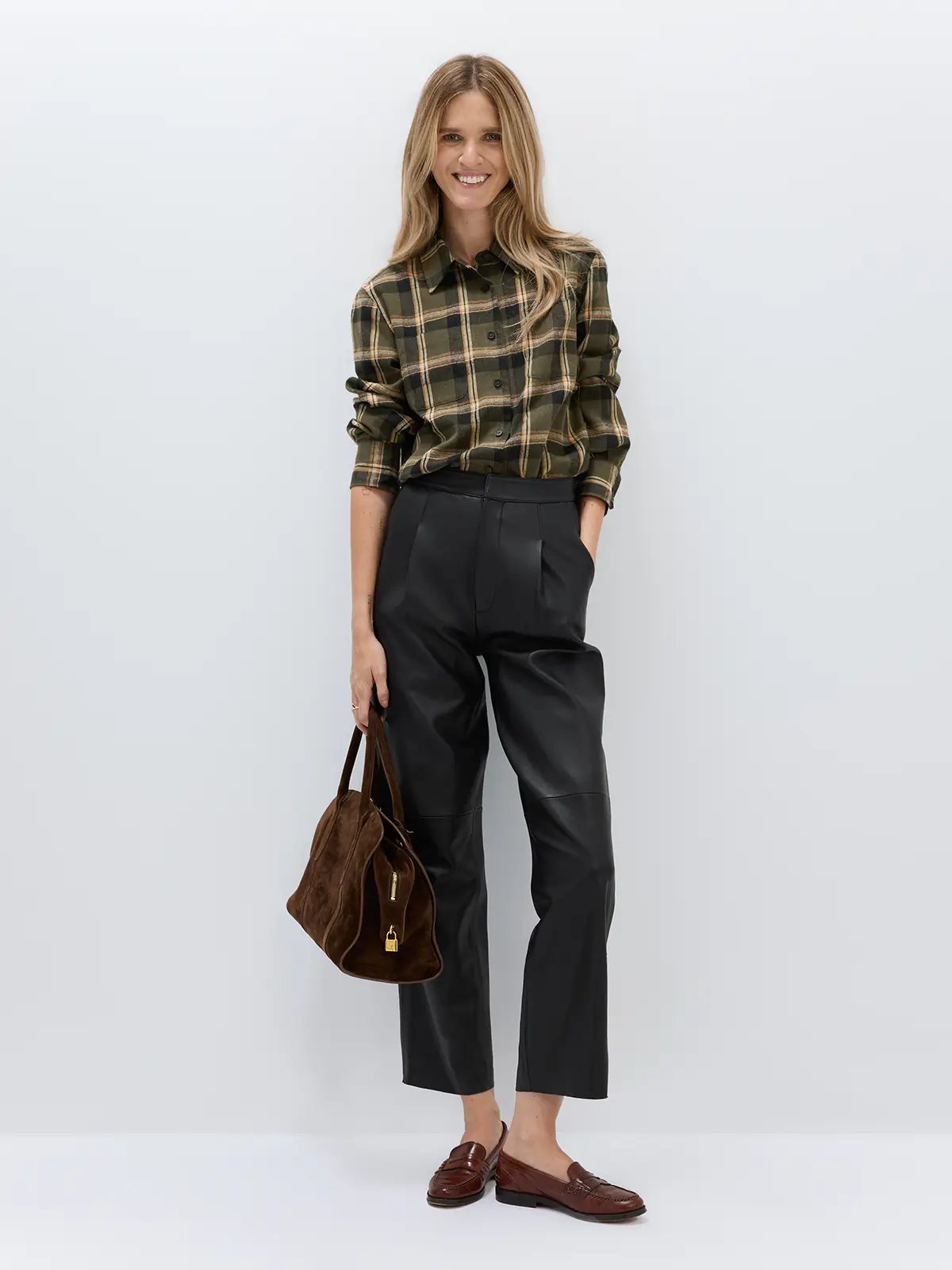 Black sheepskin leather casual pants with pleated front, cropped length, and side pockets, worn with a black textured jacket and heels.