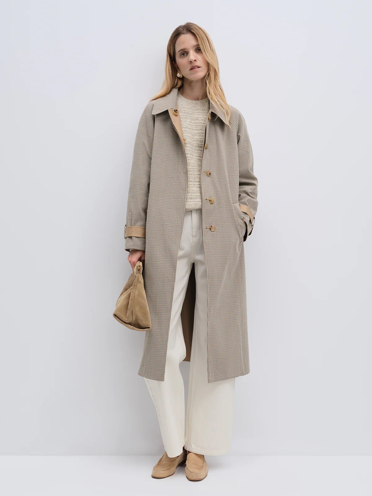 Model wearing a Khaki reversible check trench coat with buttons, paired with jeans and holding a bag.