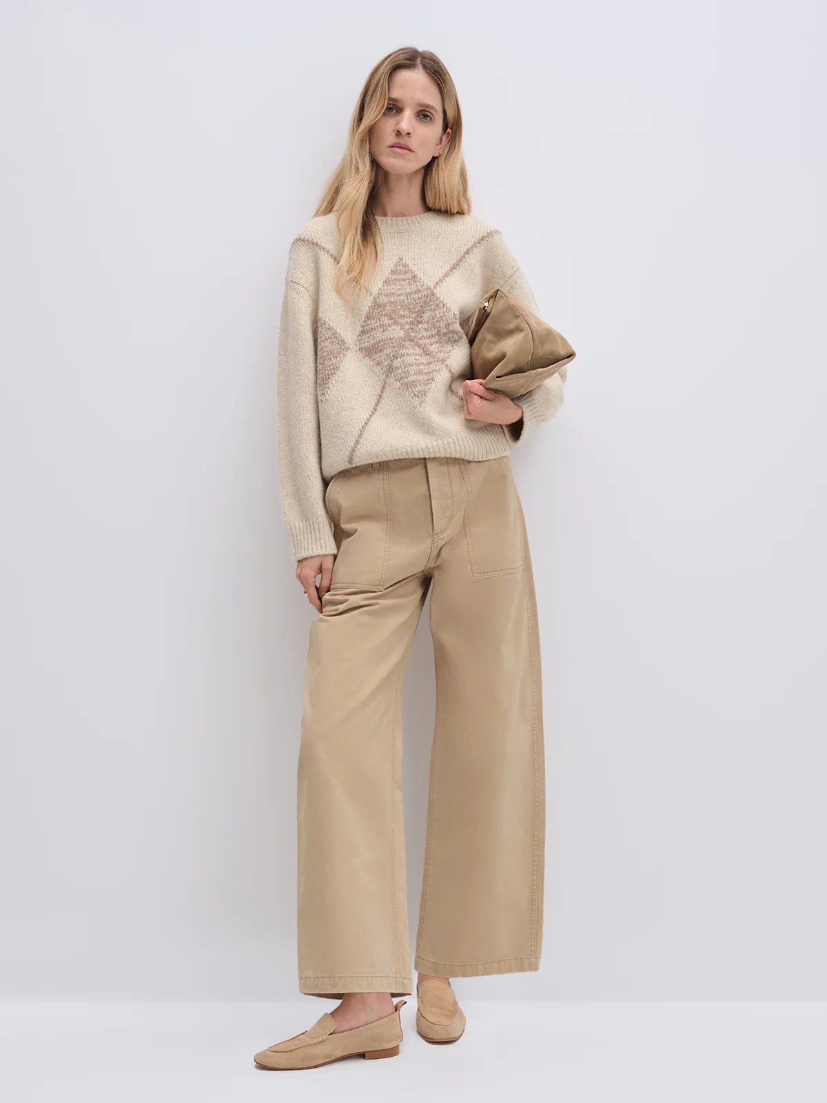 Front view of model wearing the Oatmeal PHOEBE jacquard jumper with prominent diamond pattern, paired with wide-leg trousers and holding a clutch.