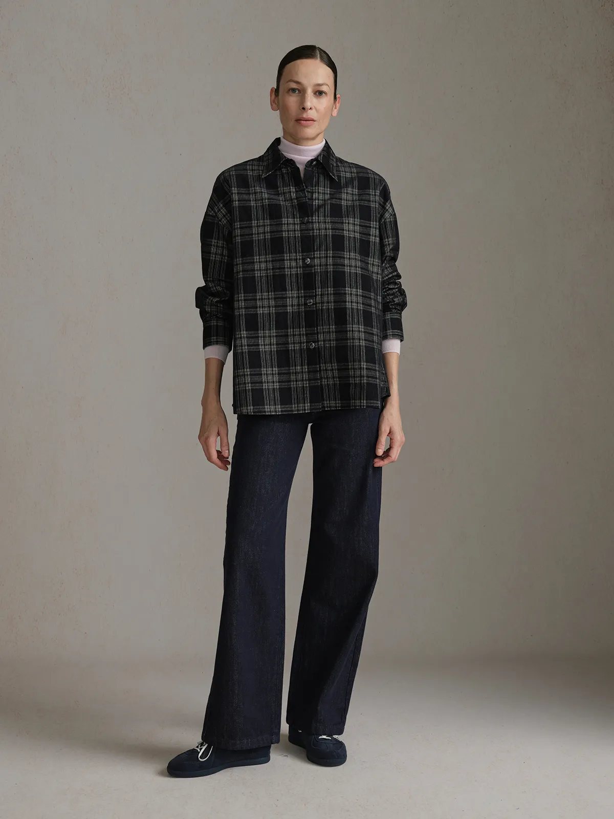 Full front pose of model in ALDER corduroy overshirt with rolled sleeves over lavender turtleneck and dark denim