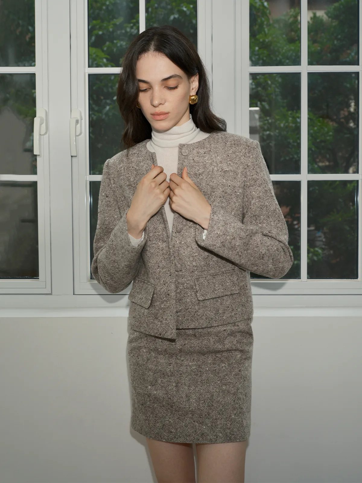 Close-up of model adjusting CLARKE tweed jacket front—highlighting button closure and collar detail