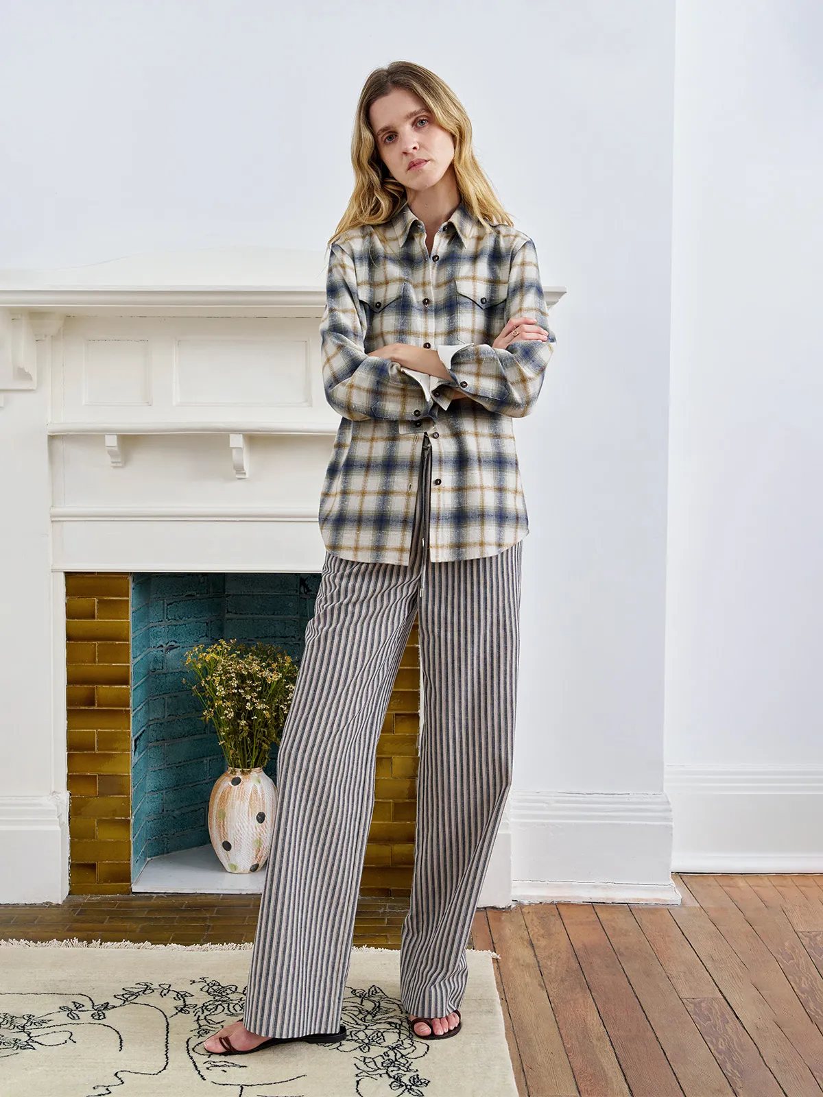 Andreatang BRAMBLE shirt with striped wide-leg trousers, standing before fireplace