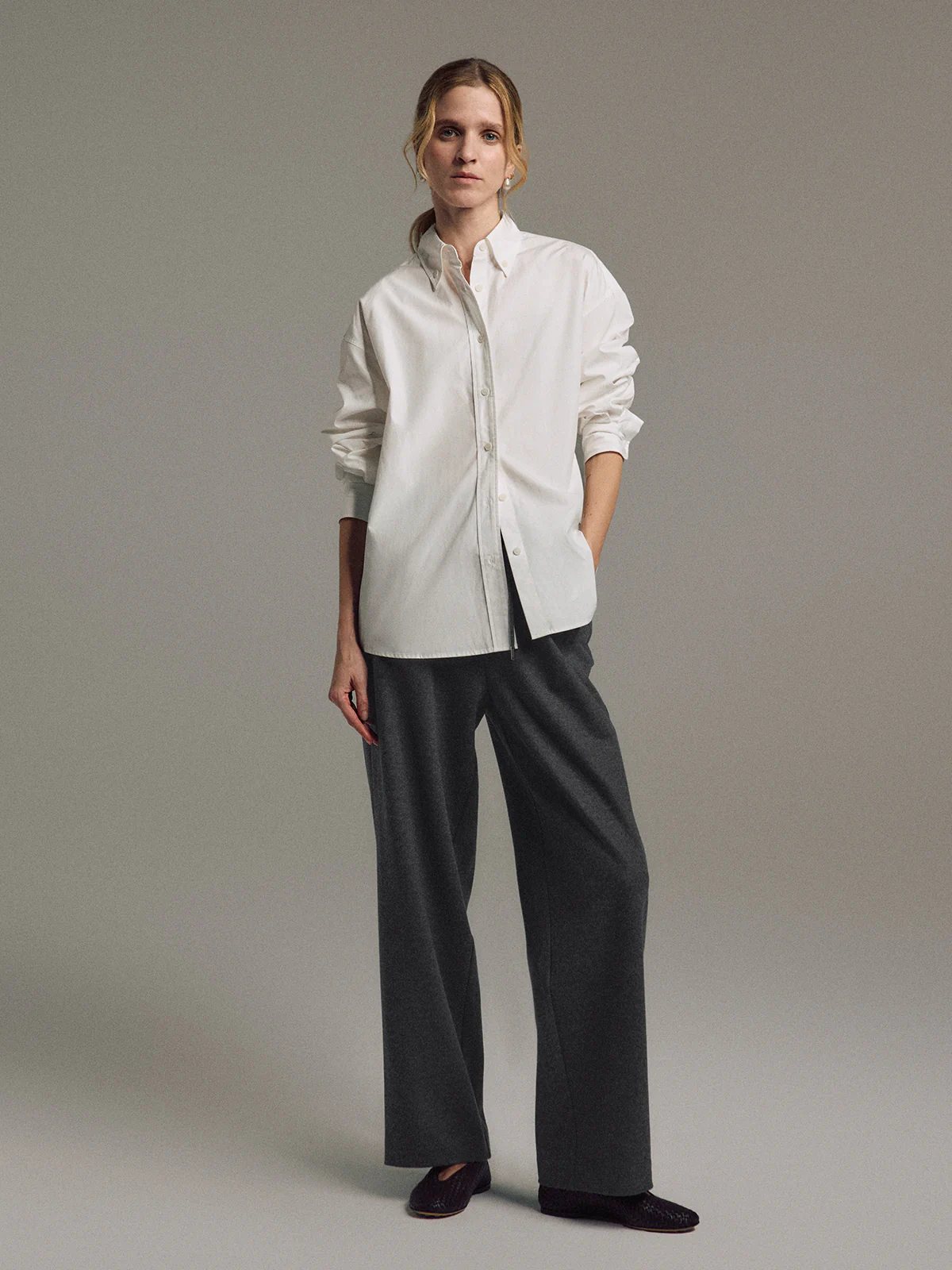 Front view of model wearing Dark Gray wool blend straight trousers with drawstring waist and hands in pockets.