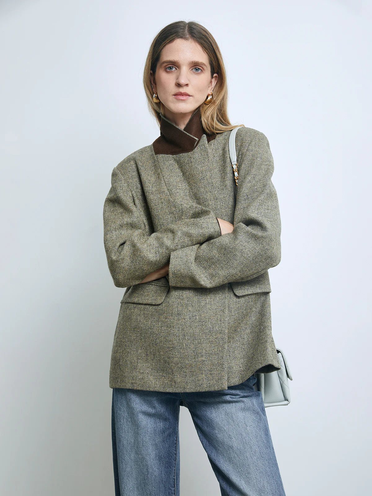 Side view of a model wearing a Sage Green pure wool tweed double-breasted blazer with jeans, loafers, and socks.
