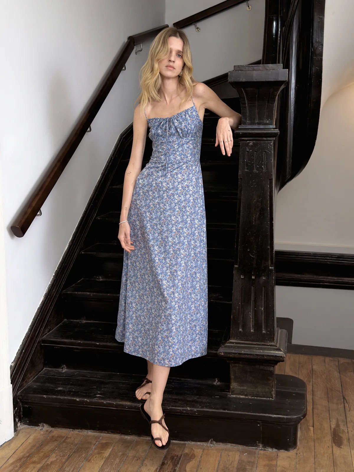 Andreatang PIPPA blue floral cami maxi dress worn by model on vintage black staircase, quiet luxury minimalist style