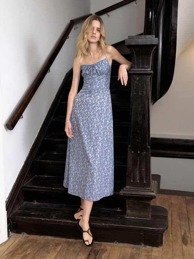 Andreatang PIPPA blue floral cami maxi dress worn by model on vintage black staircase, quiet luxury minimalist style