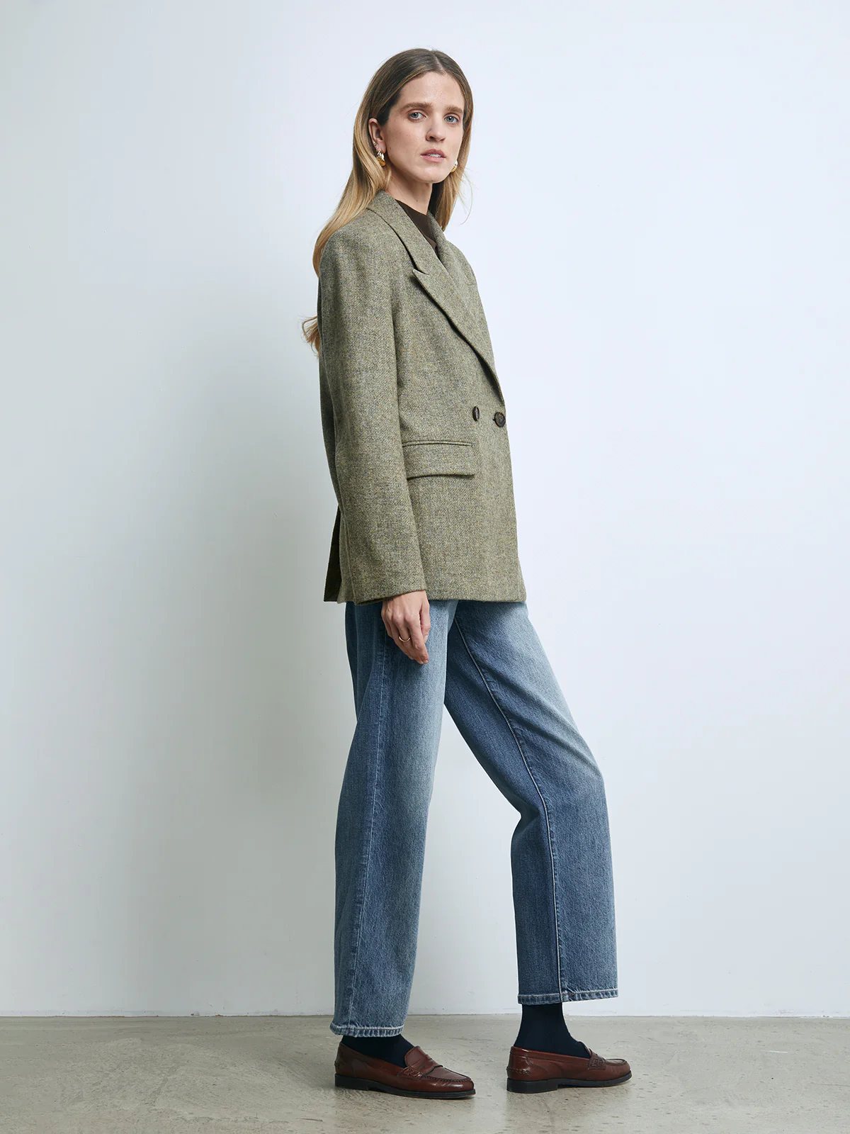 Model in a Sage Green pure wool tweed double-breasted blazer layered over a shirt, paired with wide-leg jeans and flats.