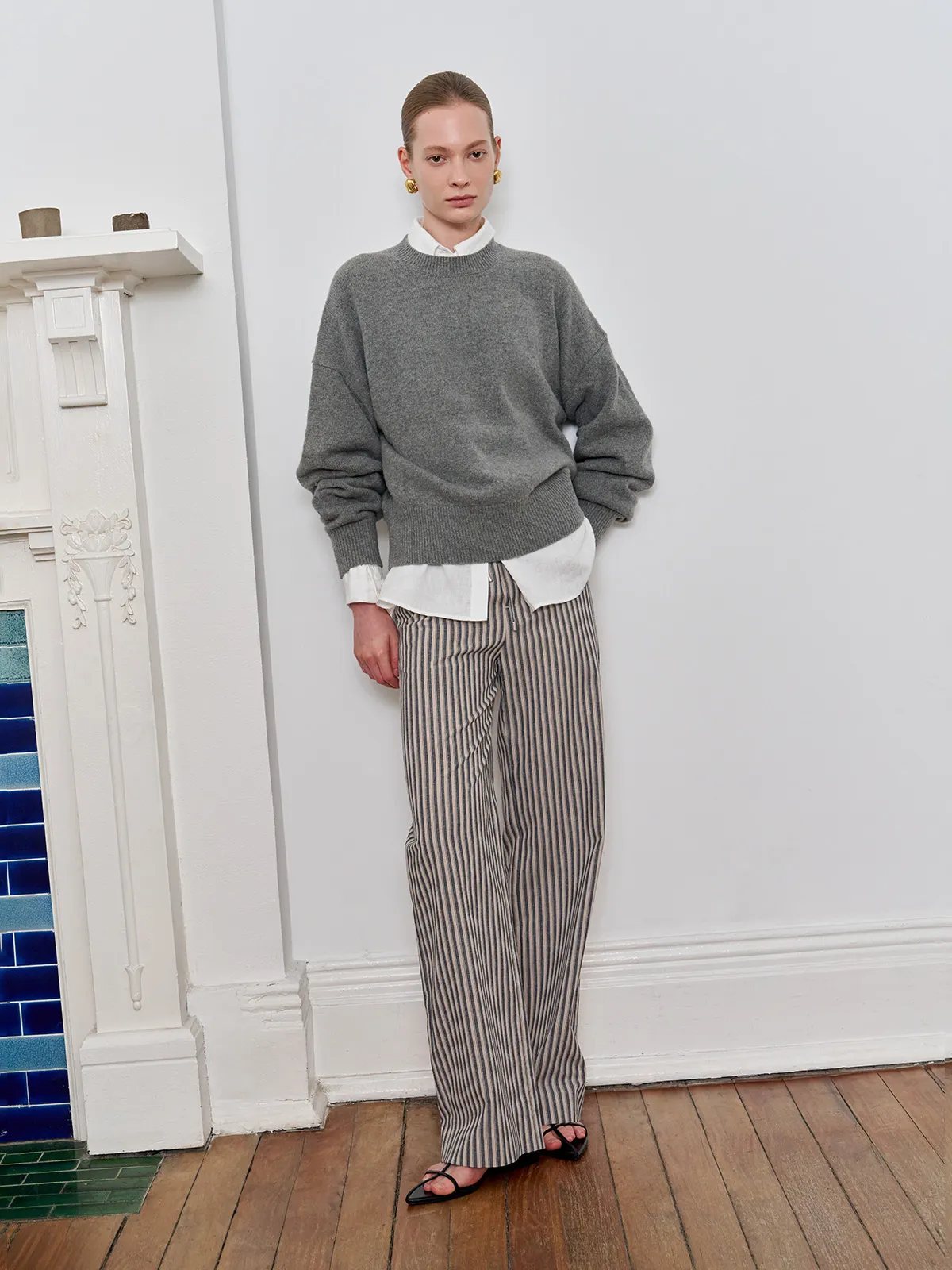 Model in oversized grey sweater layered over white shirt, paired with WHIMSY wide leg trousers