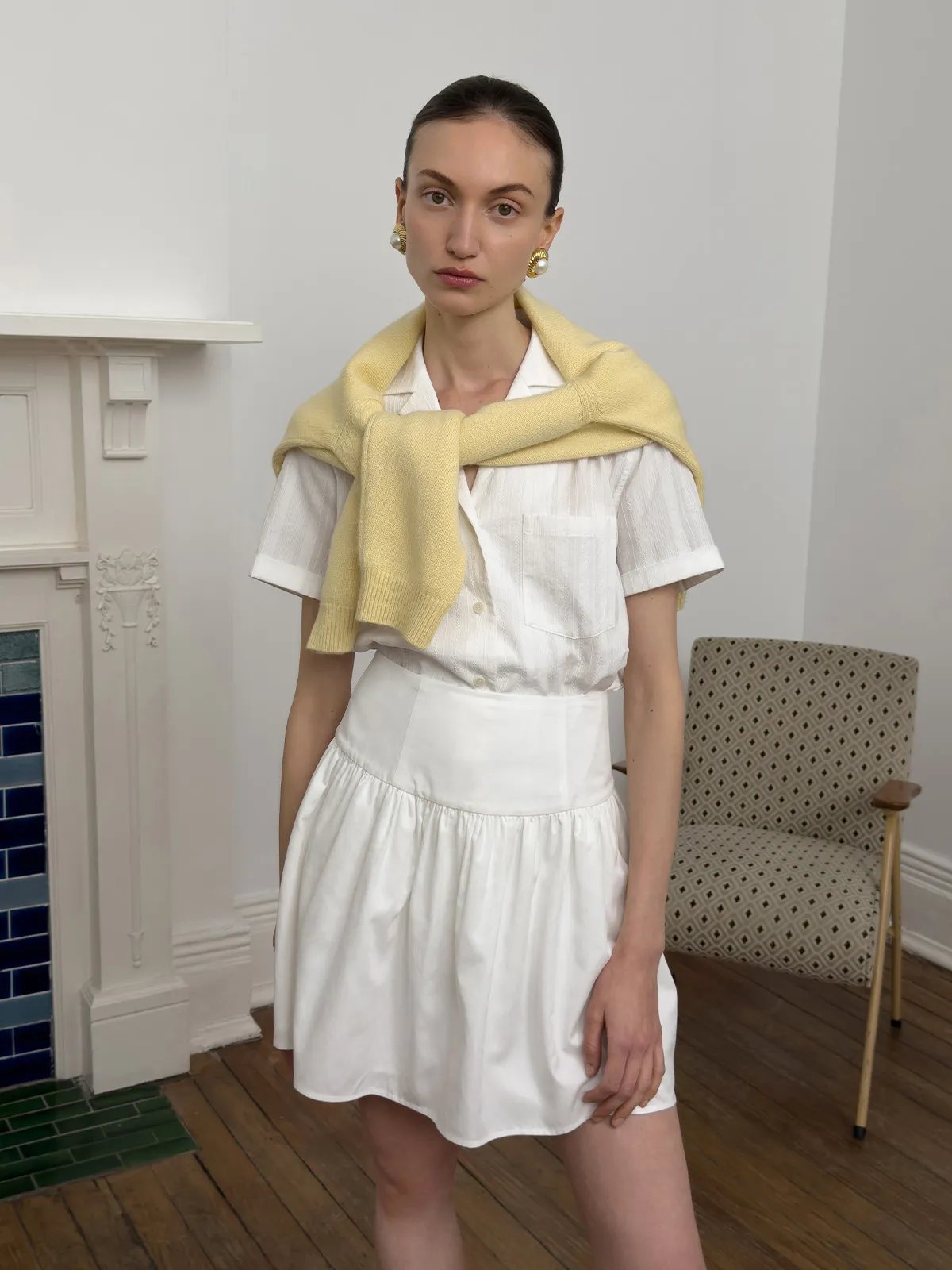 Model in layered look: white mini skirt, striped shirt, and draped yellow cashmere sweater