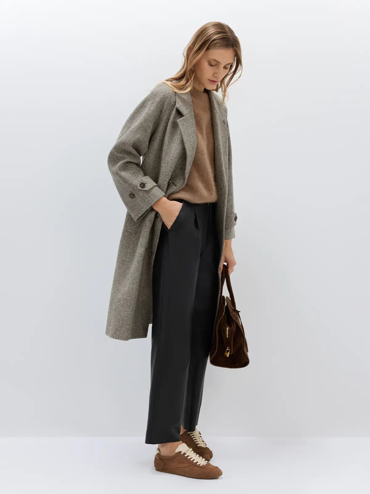 Side view of black sheepskin leather casual pants paired with a plaid shirt, bag, and loafers.