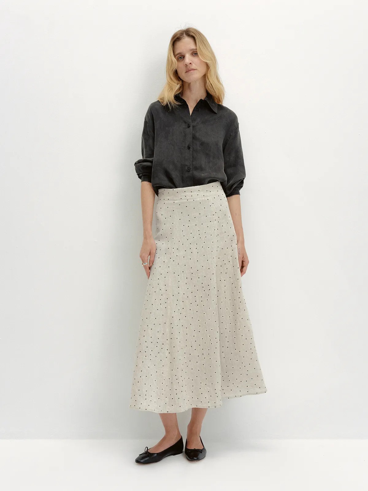 Full-body look: Model in NOBU Shirt styled with polka-dot linen midi skirt and black ballet flats