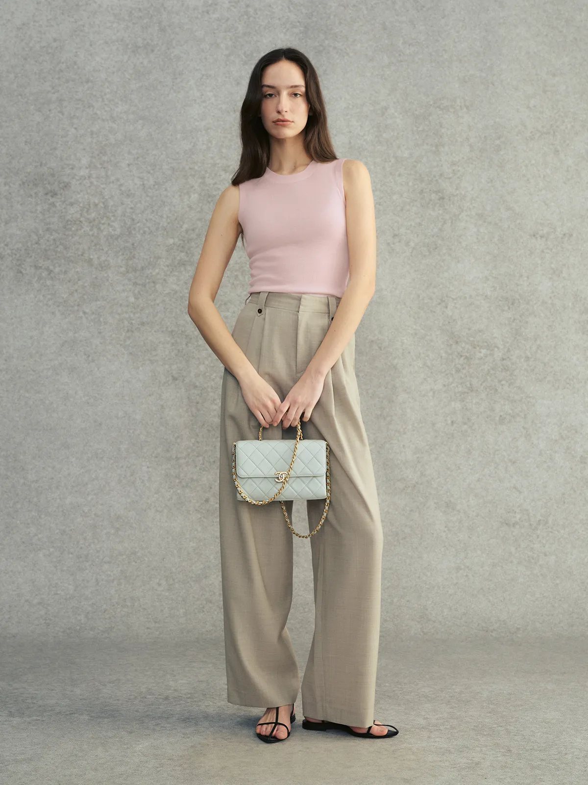 Model in blush pink DELIA knit top with stone grey trousers and mint quilted Chanel bag