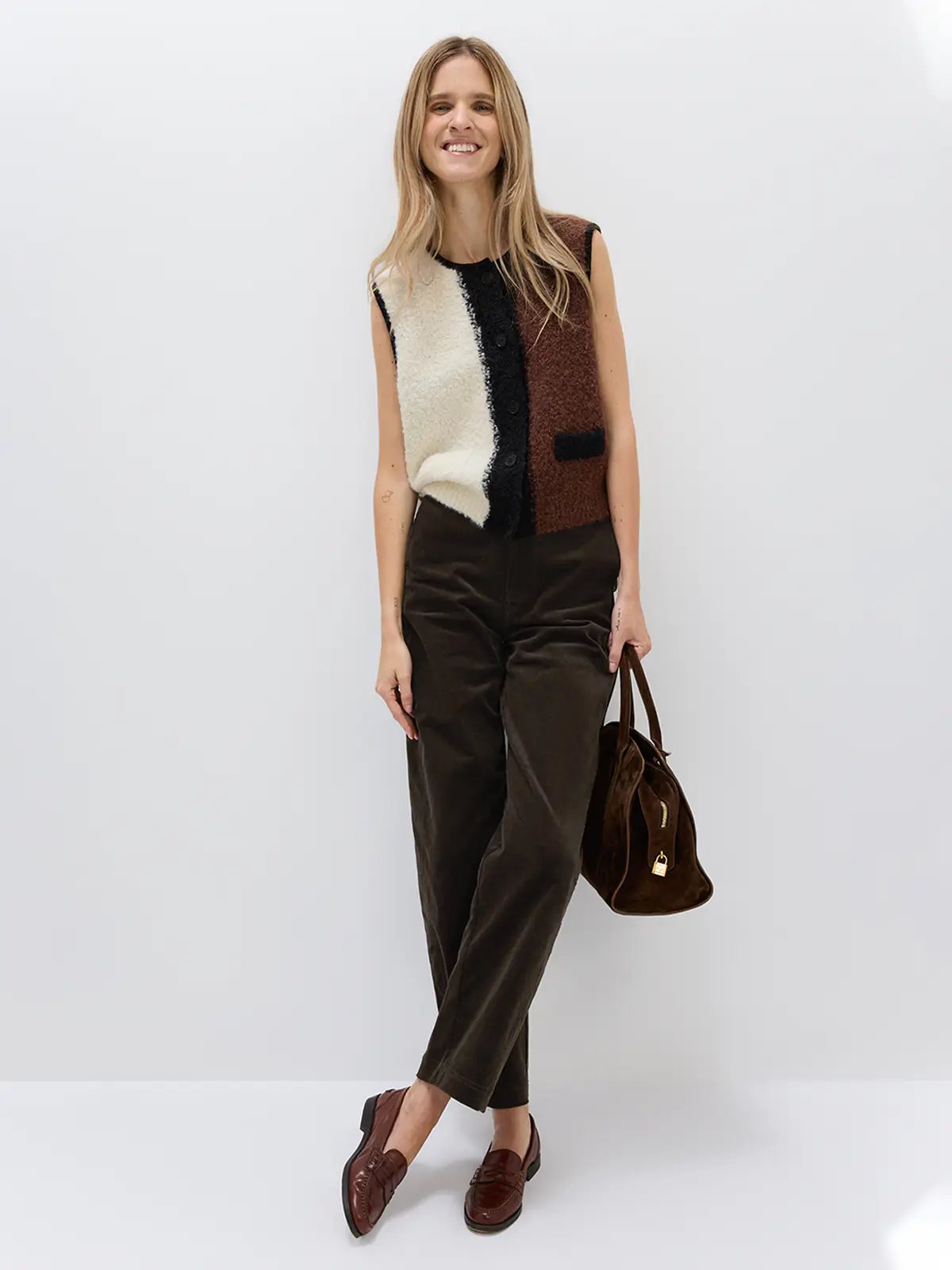Model wears the Brown/White/Black colorblock knitted vest over a black turtleneck and black skirt with knee-high boots.