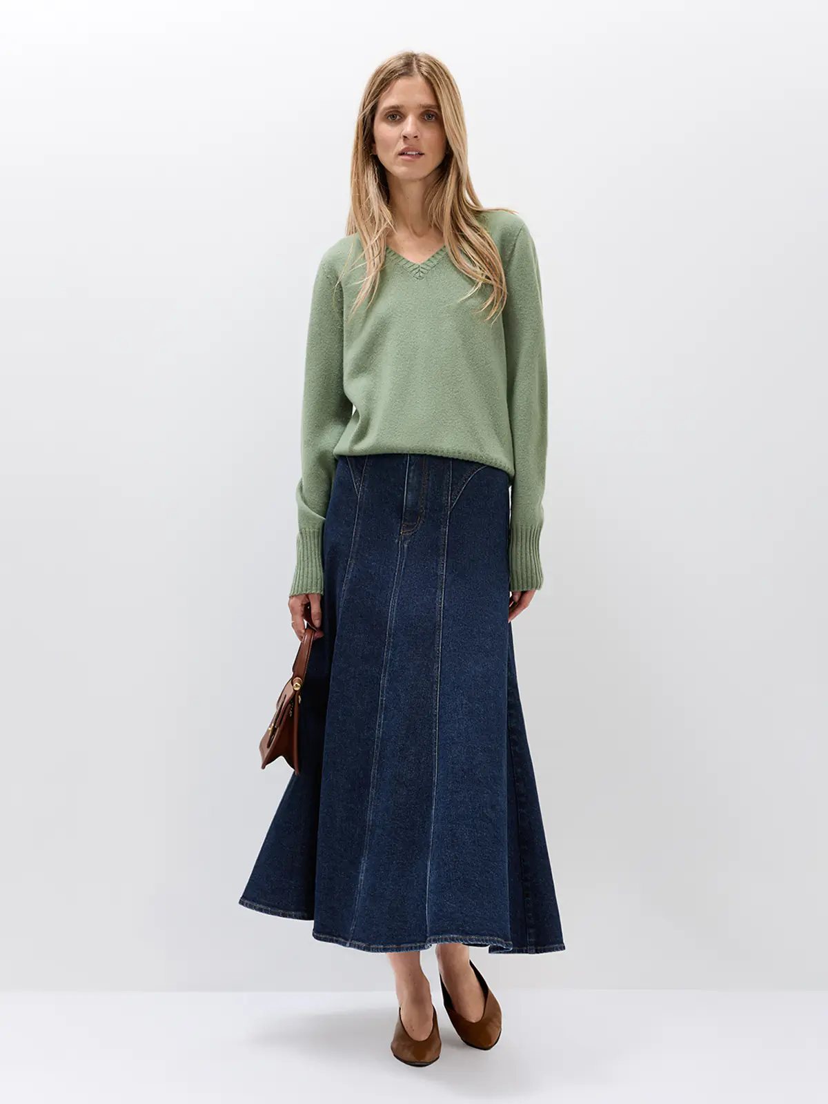 Model wearing a green Merino Wool V-Neck Jumper with wide-leg trousers and a small crossbody bag.