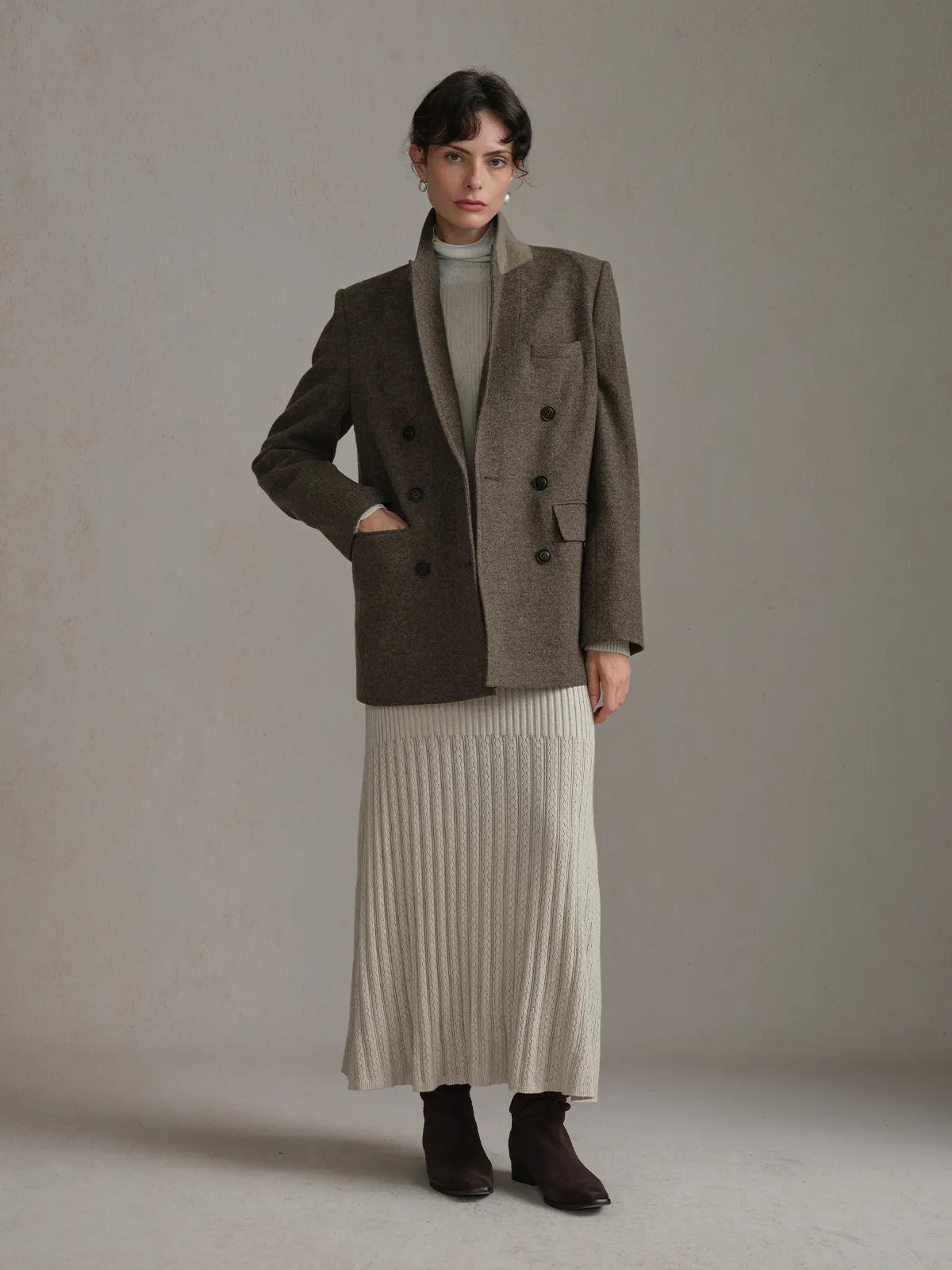 Model wearing oatmeal BRENDA dress as skirt layered under brown double-breasted wool blazer