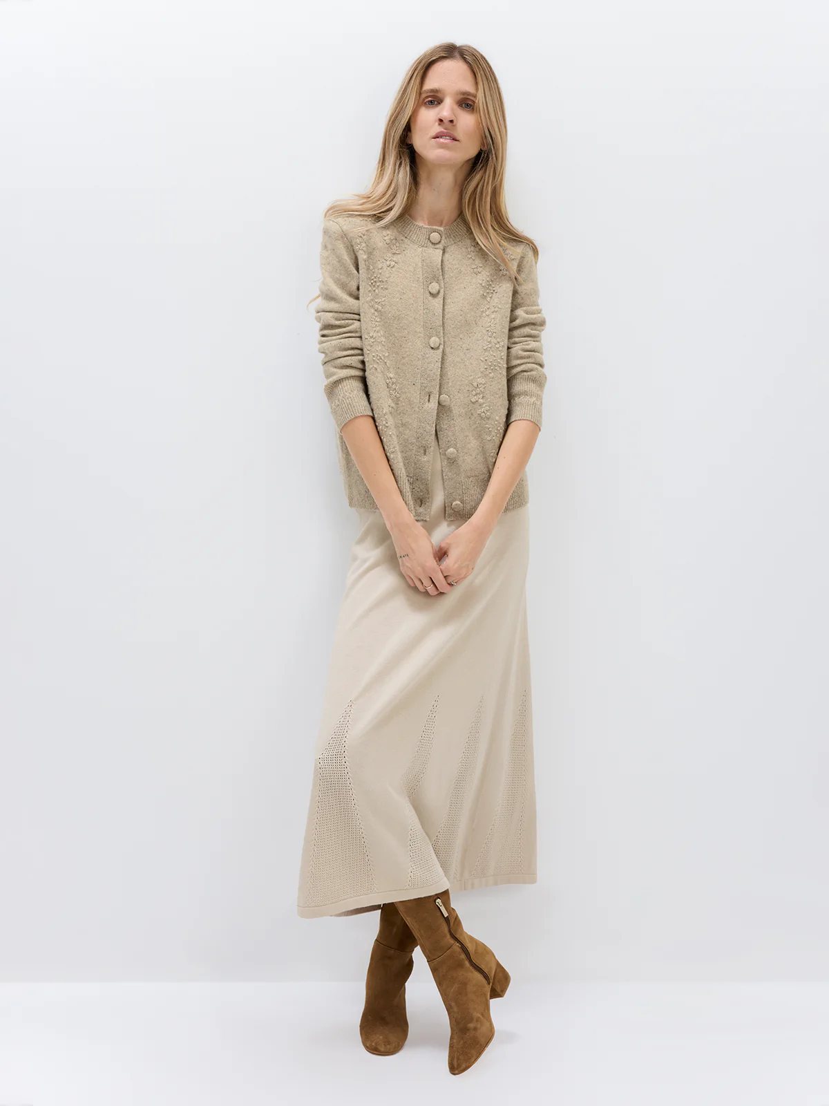 Model wearing a Light Brown Donegal knit cardigan with floral texture, button front, and ribbed cuffs, paired with a light skirt.