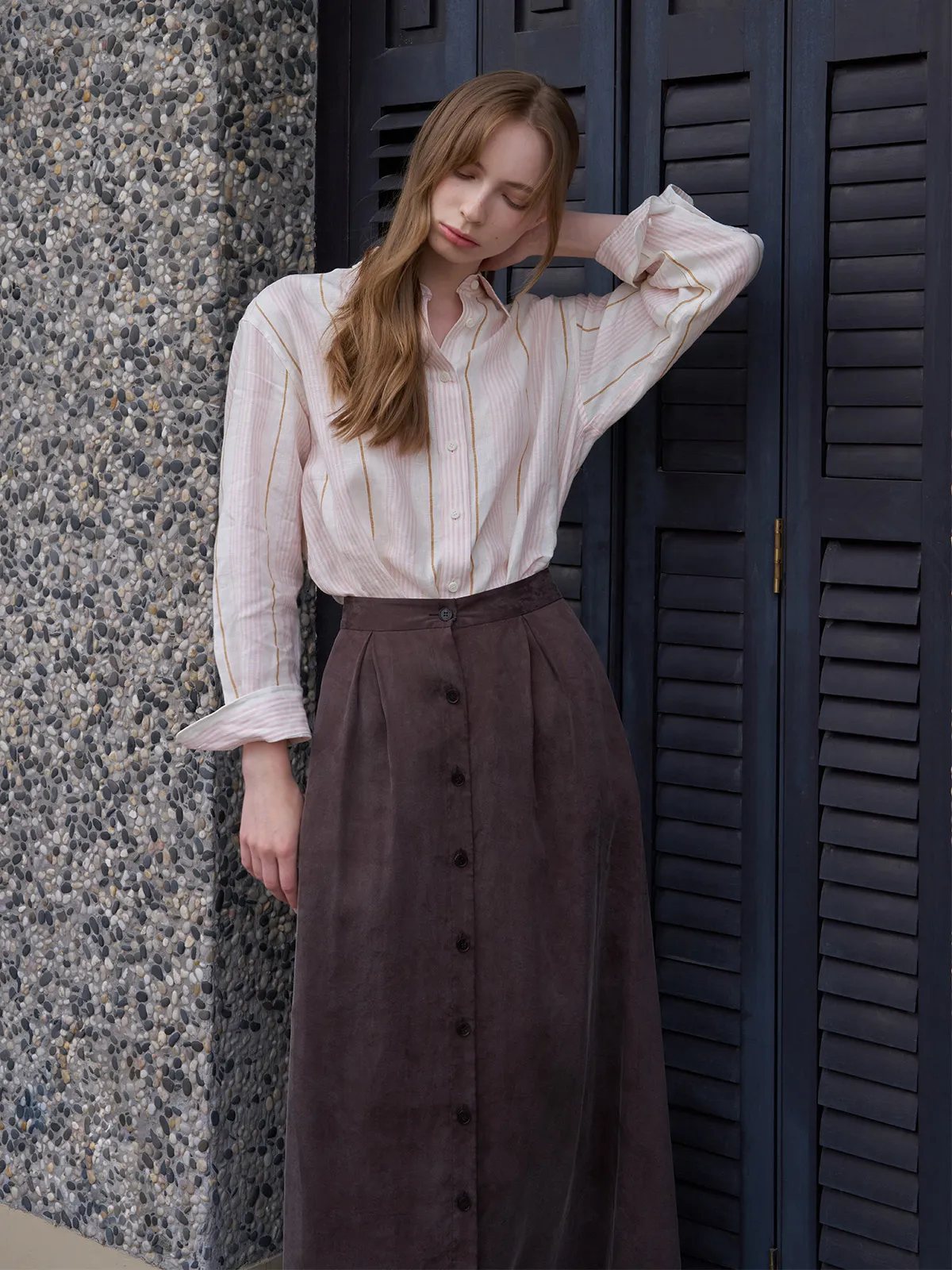 MYRA linen shirt styled with dark brown button-front maxi skirt against textured wall