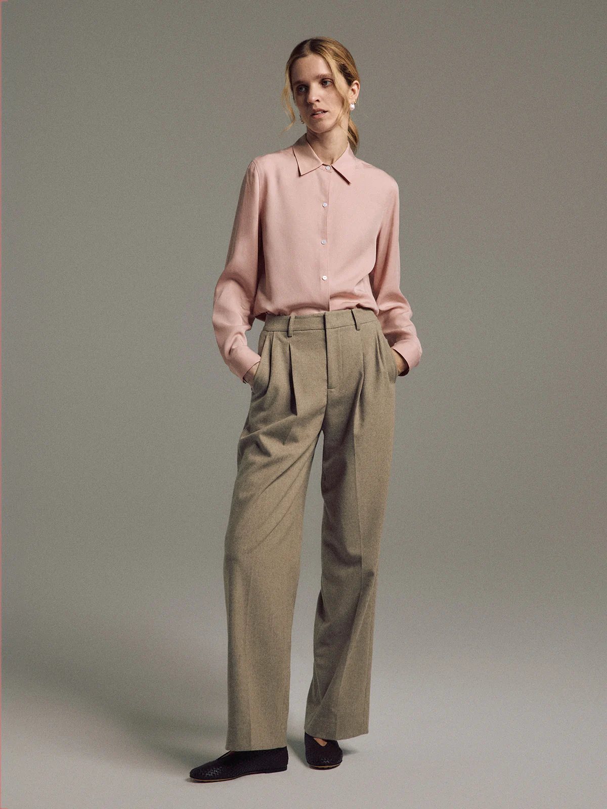 Close-up of Tan wool blend double-pleat straight-leg trousers showing waistband and front pleats.