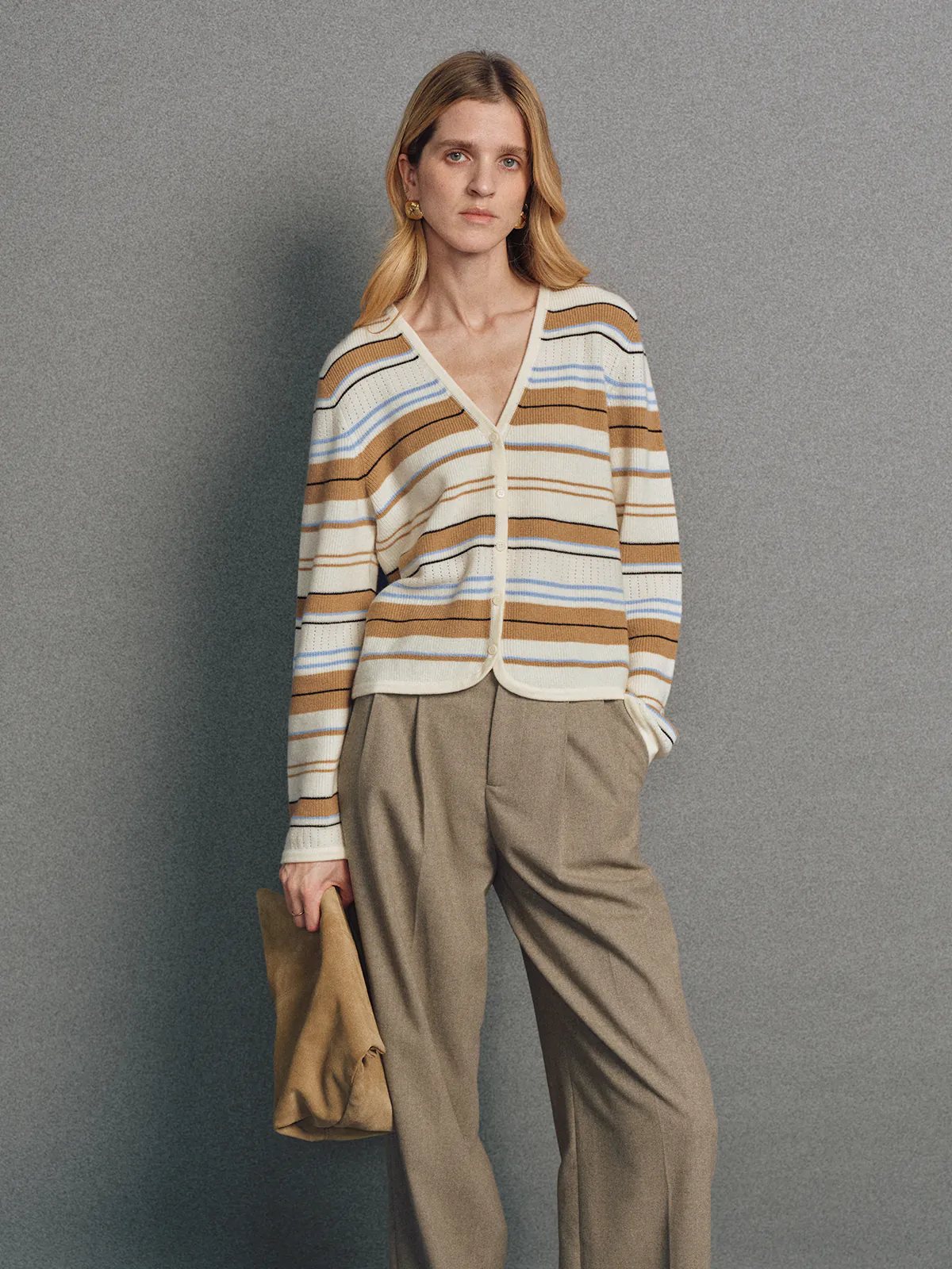 Model in the Camel multicolour stripe V-neck cardigan layered over a turtleneck and styled with trousers, standing front-facing.