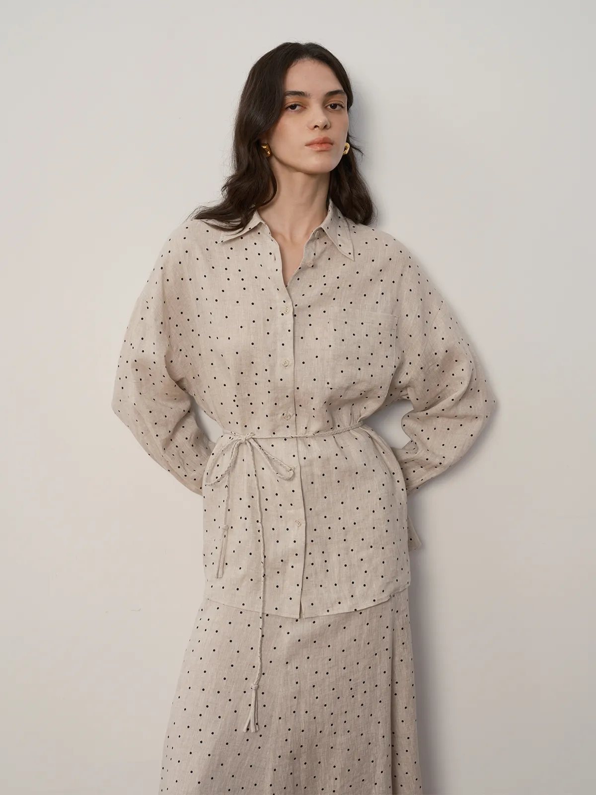 Front view of model in ODELIA linen shirt and matching polka dot skirt, hands on hips, showcasing balloon sleeves and waist tie