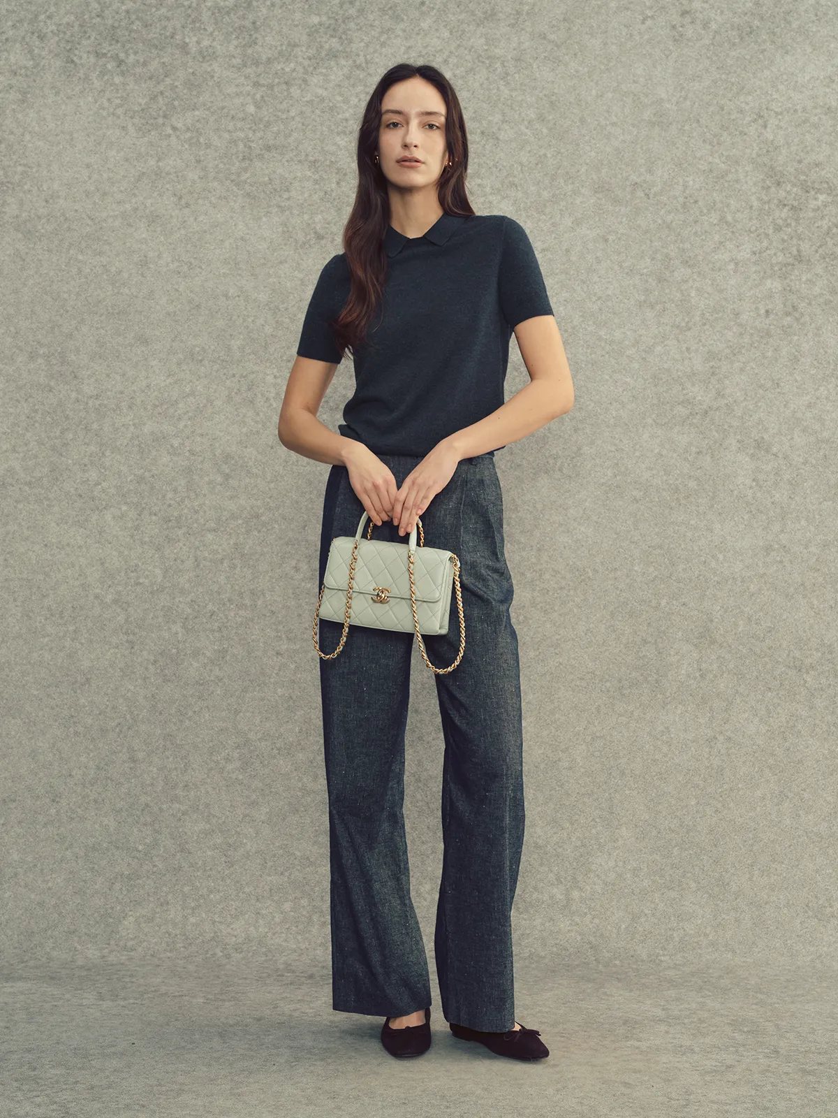 Full-body shot of model in charcoal AUDREY top, wide-leg denim, and mint Chanel-style bag