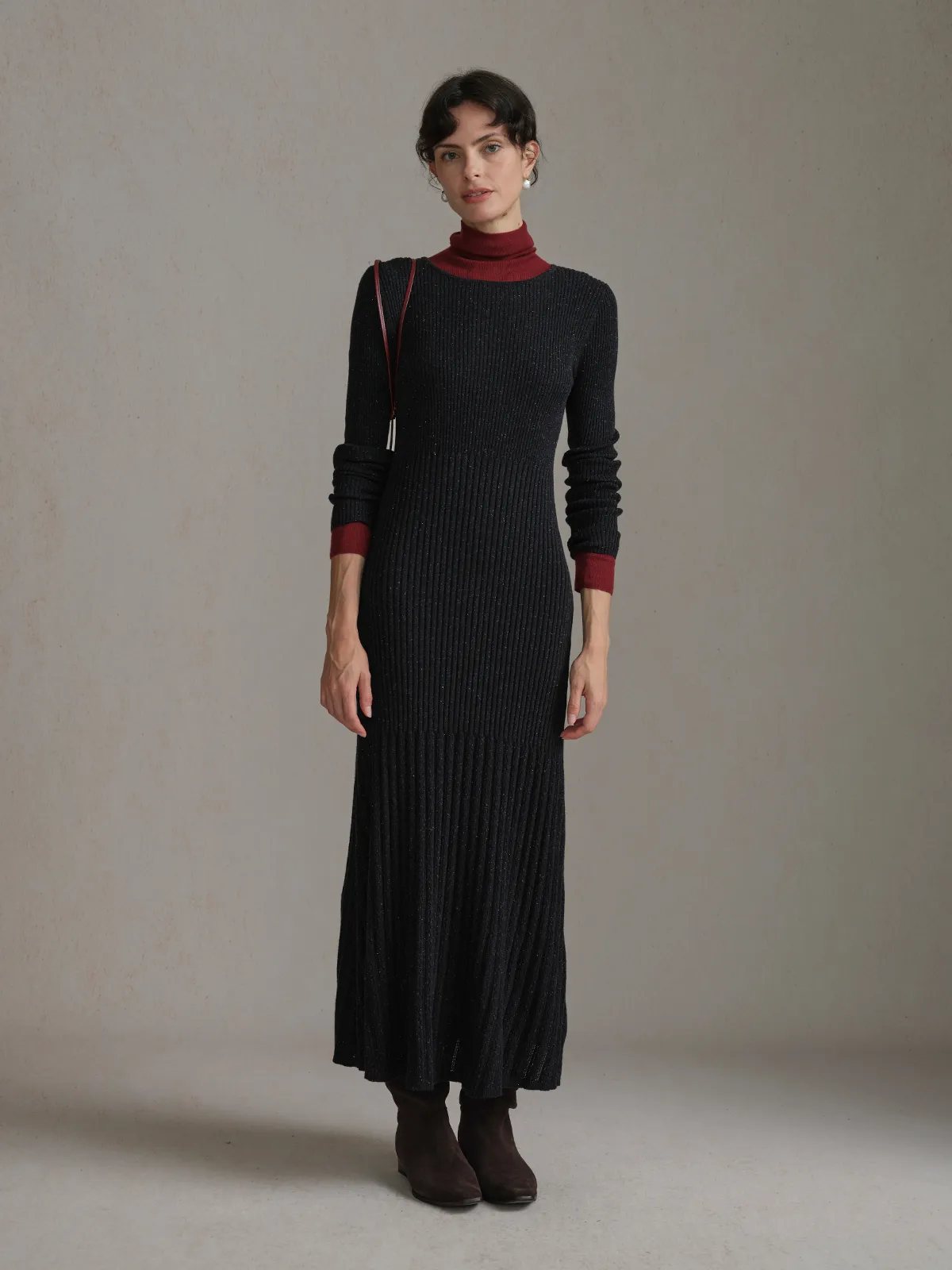 Three-quarter view of model in black BRENDA dress with burgundy turtleneck, showcasing sleeve cuff contrast and posture