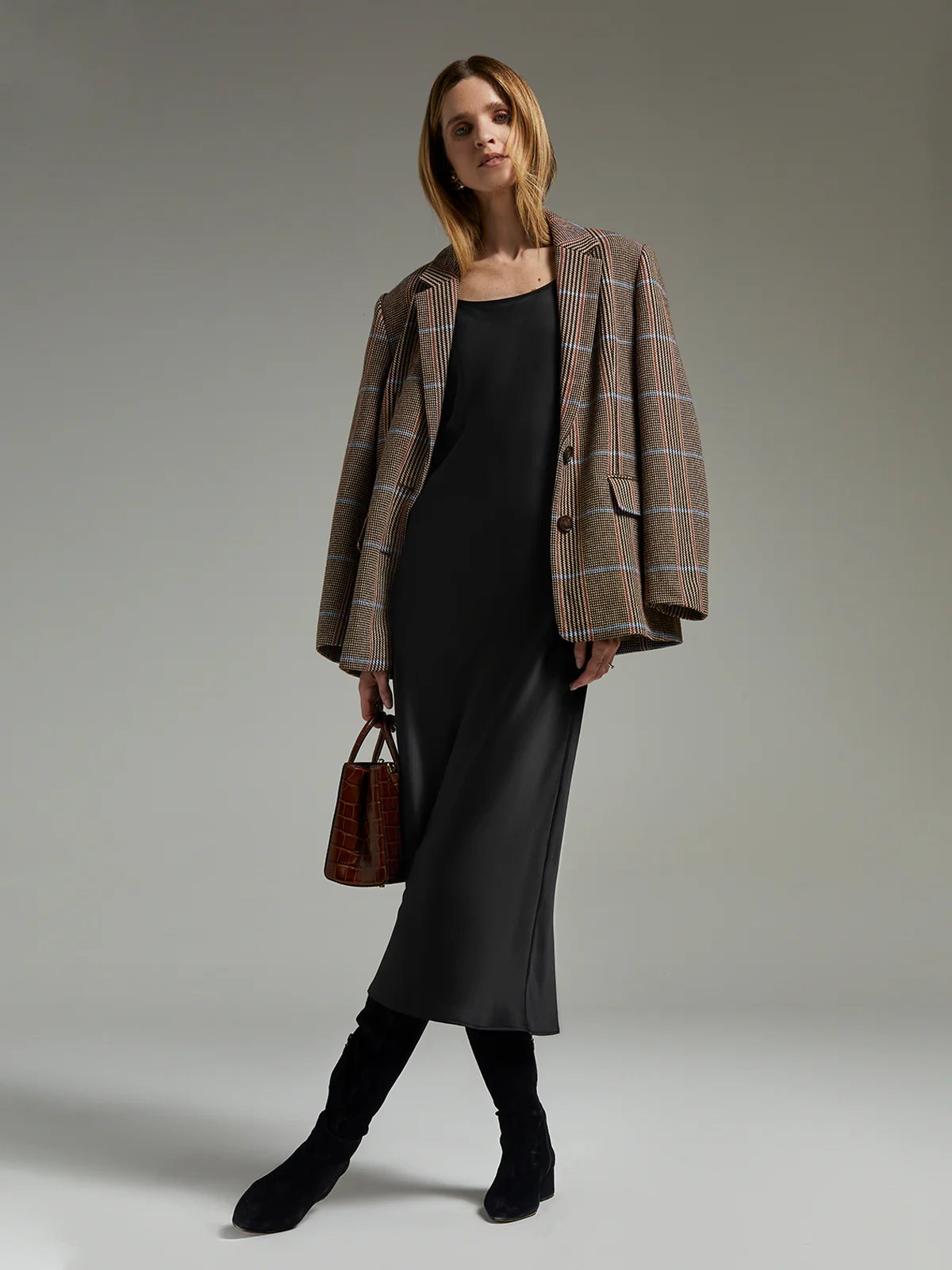 andreatang British check wool blazer layered over black slip dress with knee boots