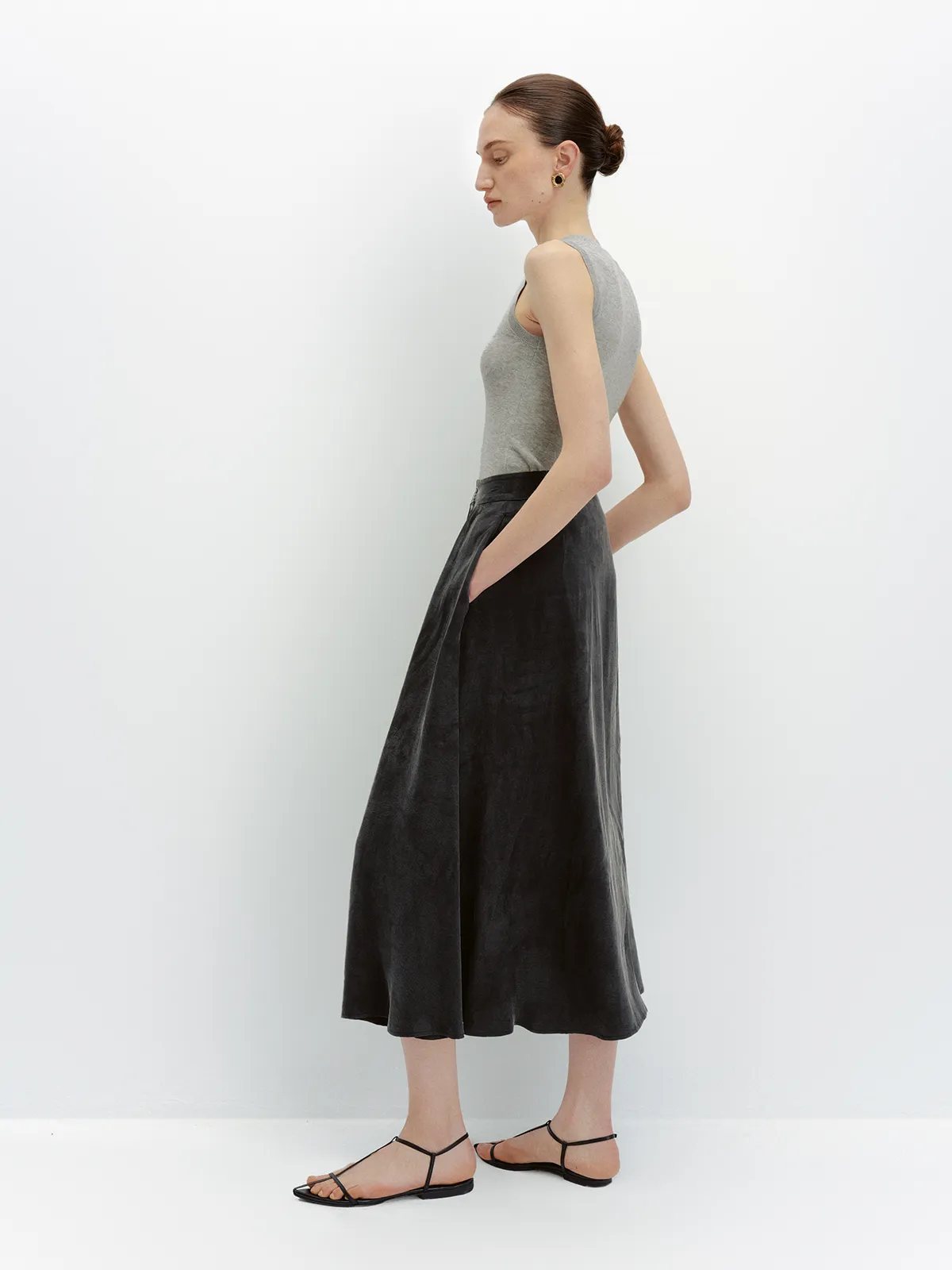 Side view of black NOBU Midi Skirt with grey tank, highlighting pocket and drape