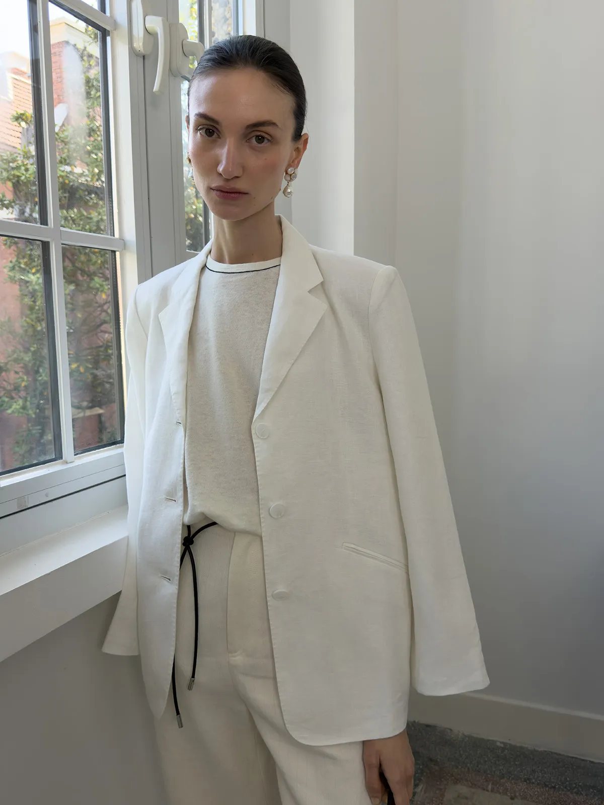 Model in ivory sleeveless knit top layered under oversized white blazer