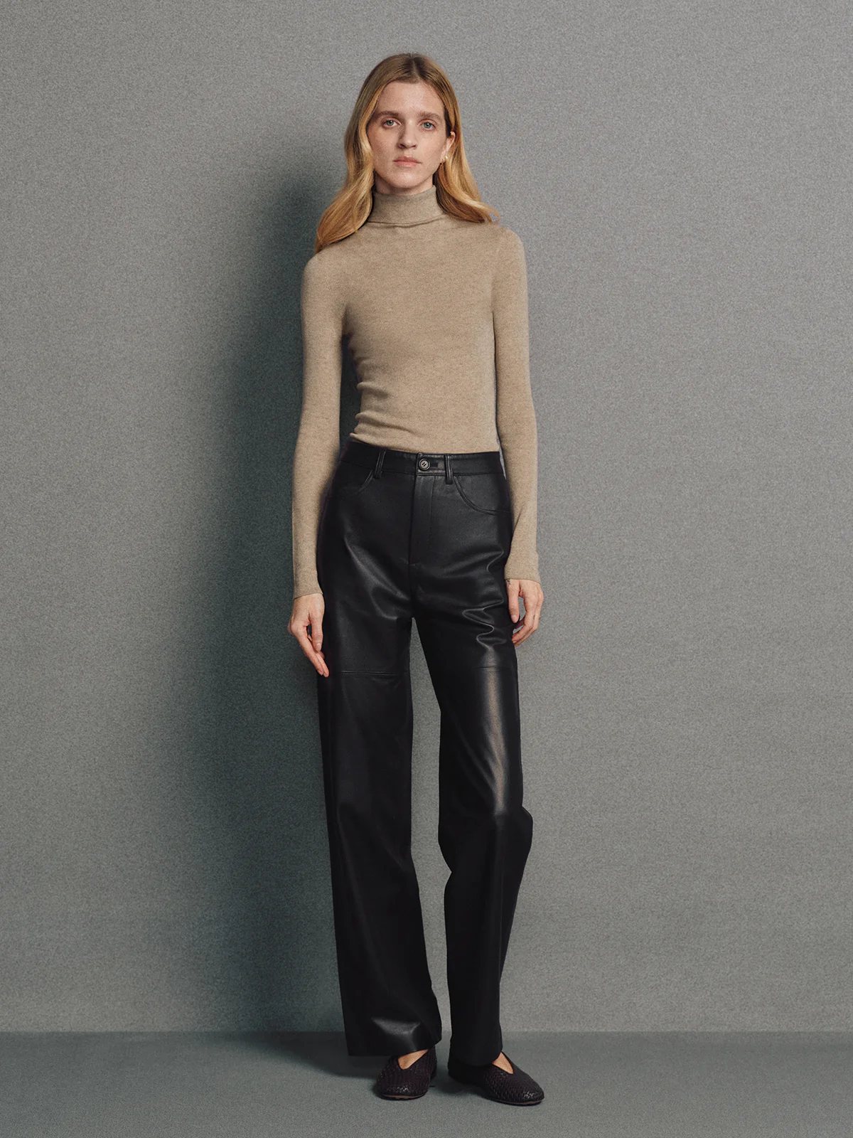 Model wearing a seamless turtleneck in Brown with leather pants and dark flats.