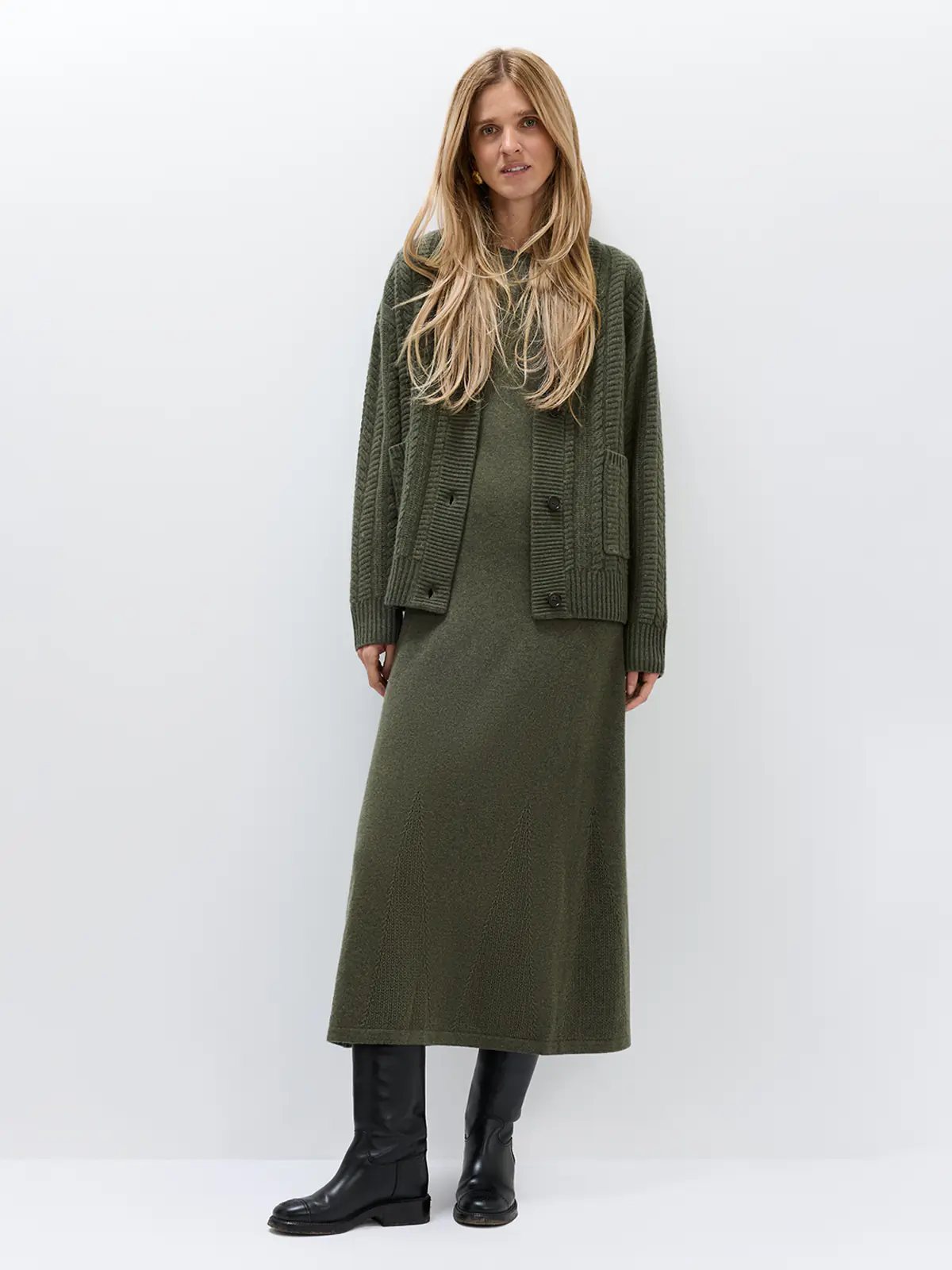 Model wearing a long-sleeve knitted dress in Green with a vented hem, front view.