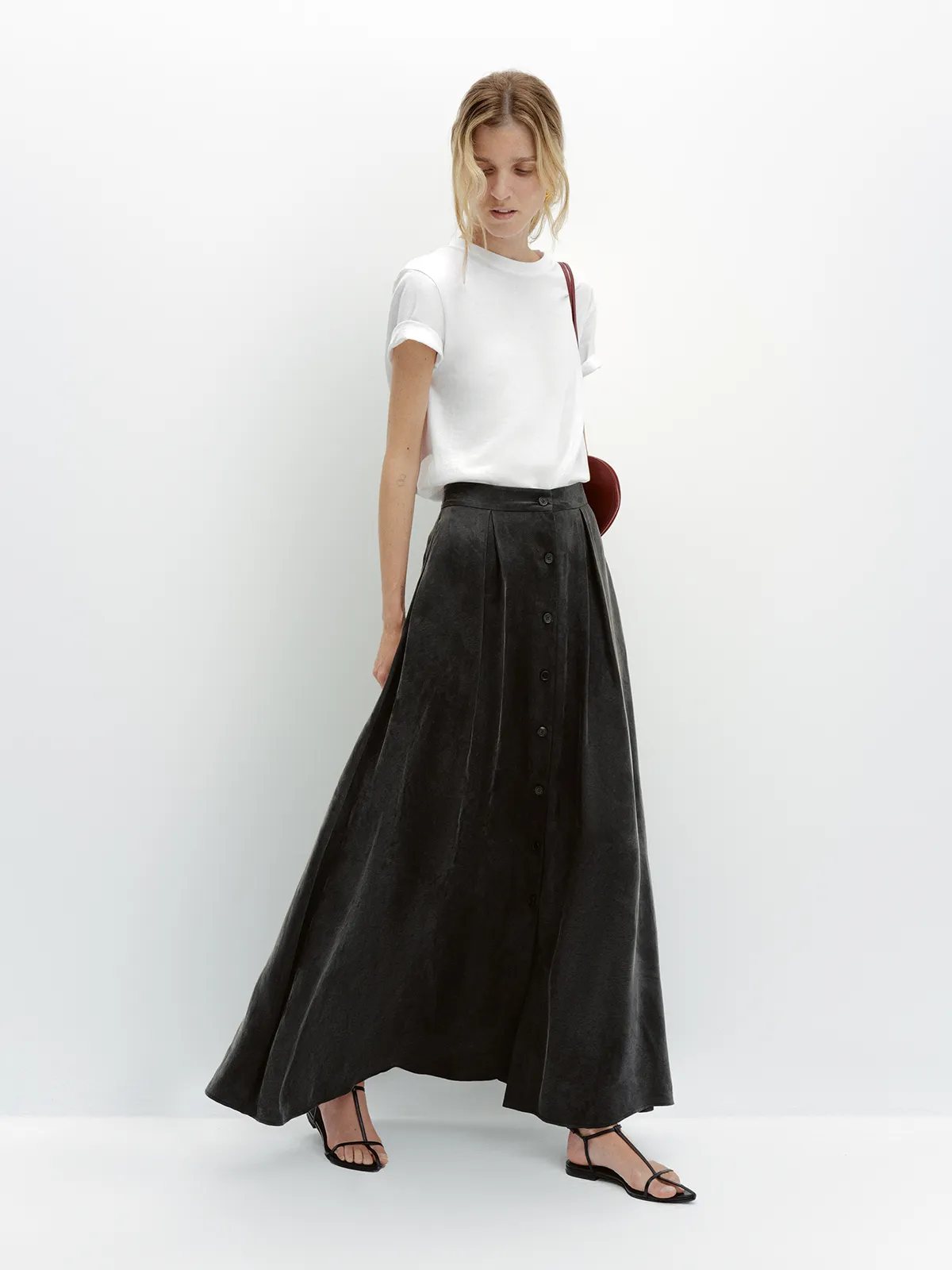 Model walking in black NOBU Maxi Skirt with white tee and strappy sandals